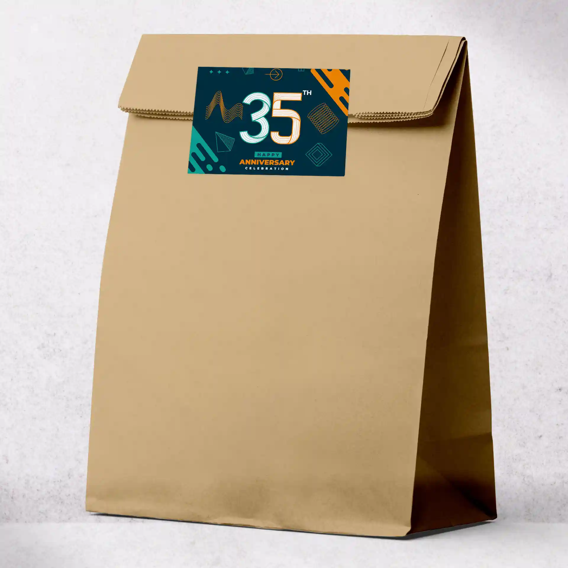 Brown paper bag with a printed rectangular label featuring a colorful design for a 35th anniversary celebration.
