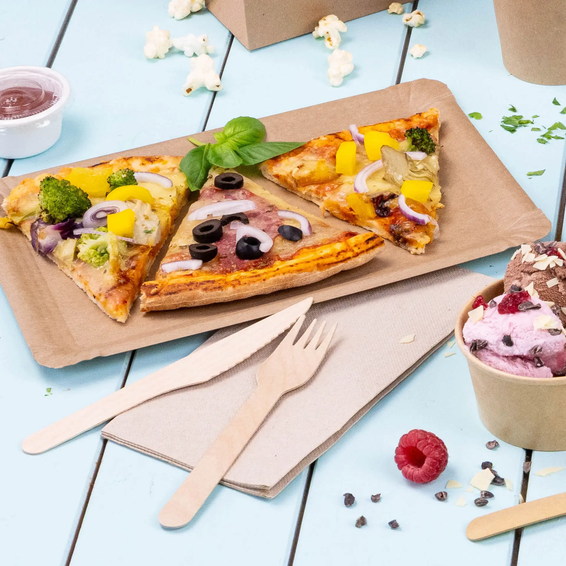 Image of three pizza slices on a brown paper tray, with wooden cutlery and a cup of ice cream nearby.