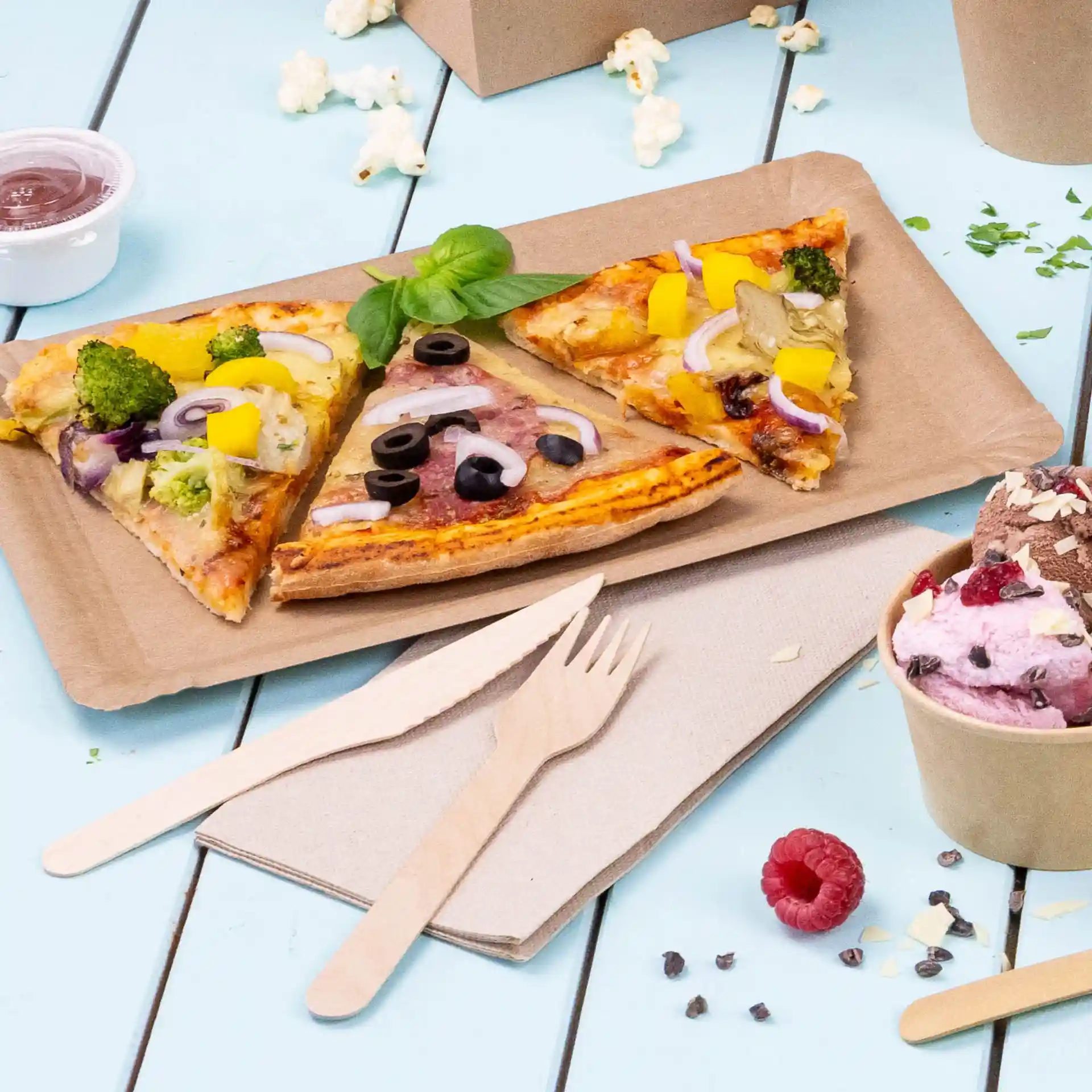 Image of three pizza slices on a brown paper tray, with wooden cutlery and a cup of ice cream nearby.