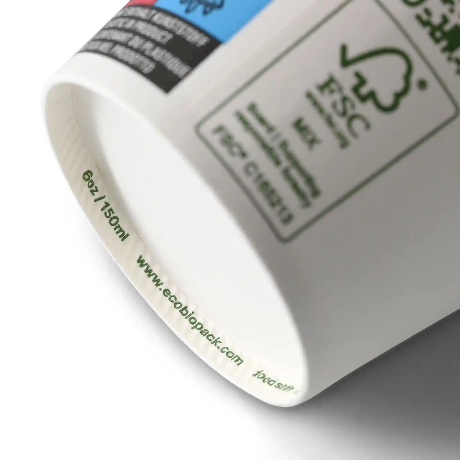 Cup with a white surface, showing a label with markings and a green circular symbol on the side.