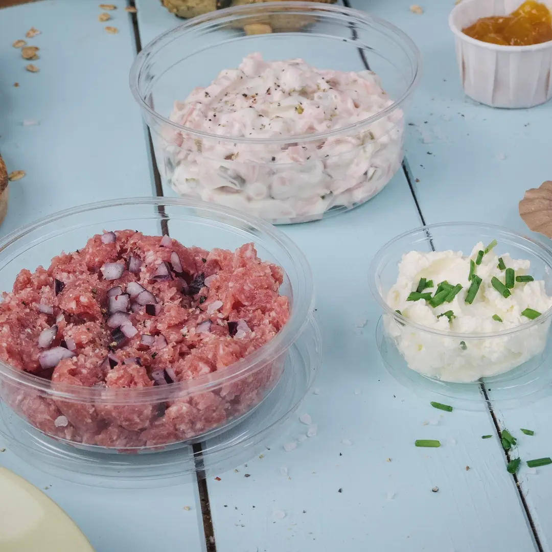 Drei transparente Behälter mit verschiedenen Aufstrichen: rosa Fleischmischung mit Zwiebeln, cremiger weißer Aufstrich und weißer Käseaufstrich mit Schnittlauch.