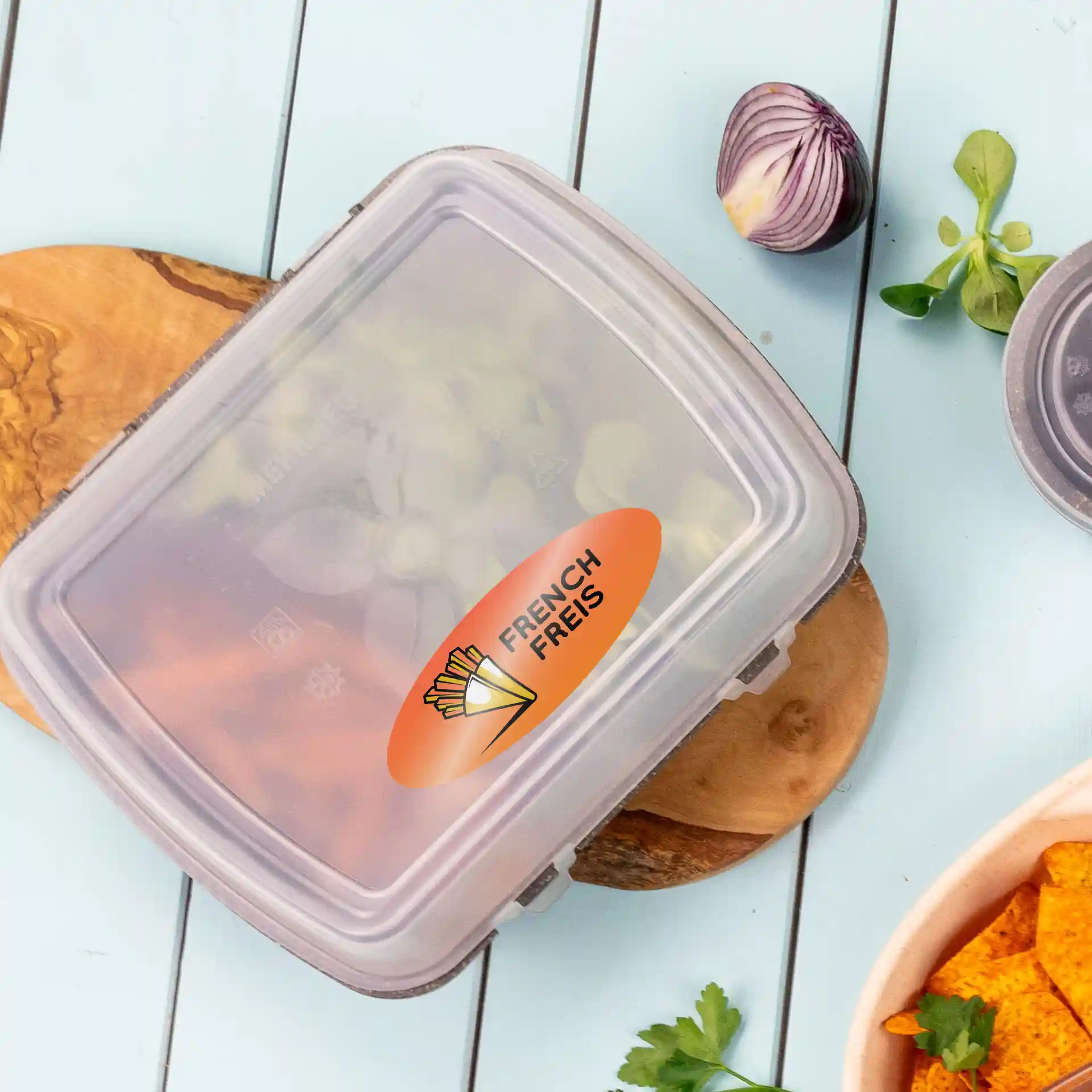 Container with a printed oval label reading "FRENCH FRIES," placed on a wooden board with vegetables nearby.