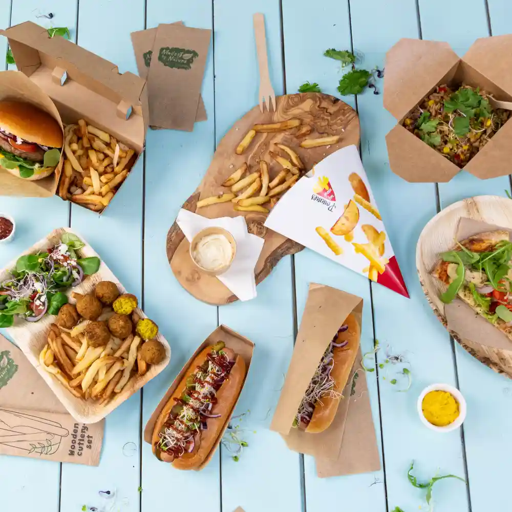 Variety of fast food items including burgers, hot dogs, fries, salad, and falafel served on wooden and paper trays.