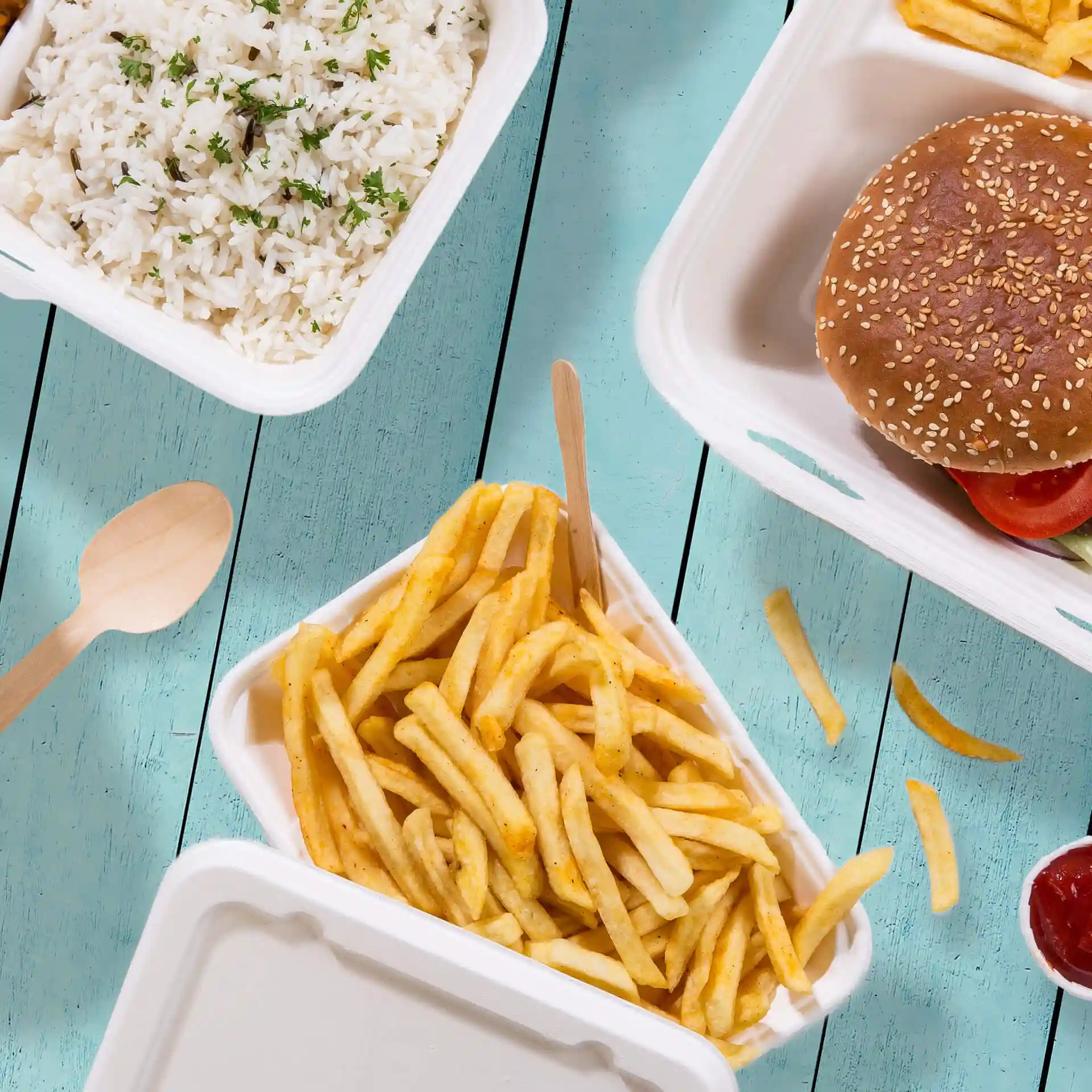 Bild einer rechteckigen weißen Zuckerrüben-Schüssel mit Pommes frites und einem Holzlöffel auf einer blauen Holzoberfläche.