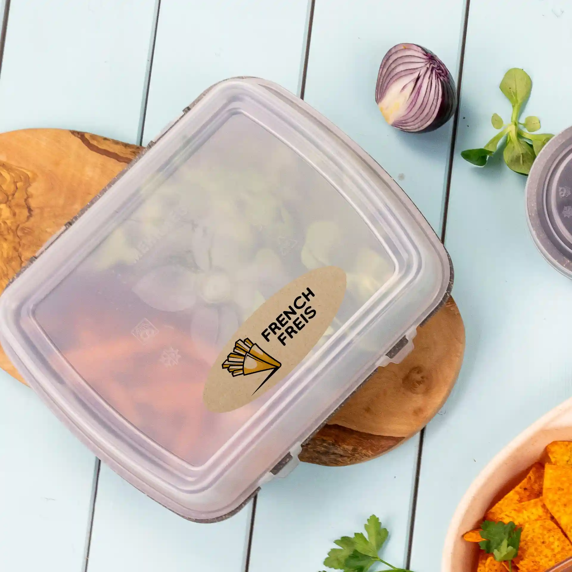 Container with a transparent lid showing a printed label reading "FRENCH FRIES," placed on a wooden board.