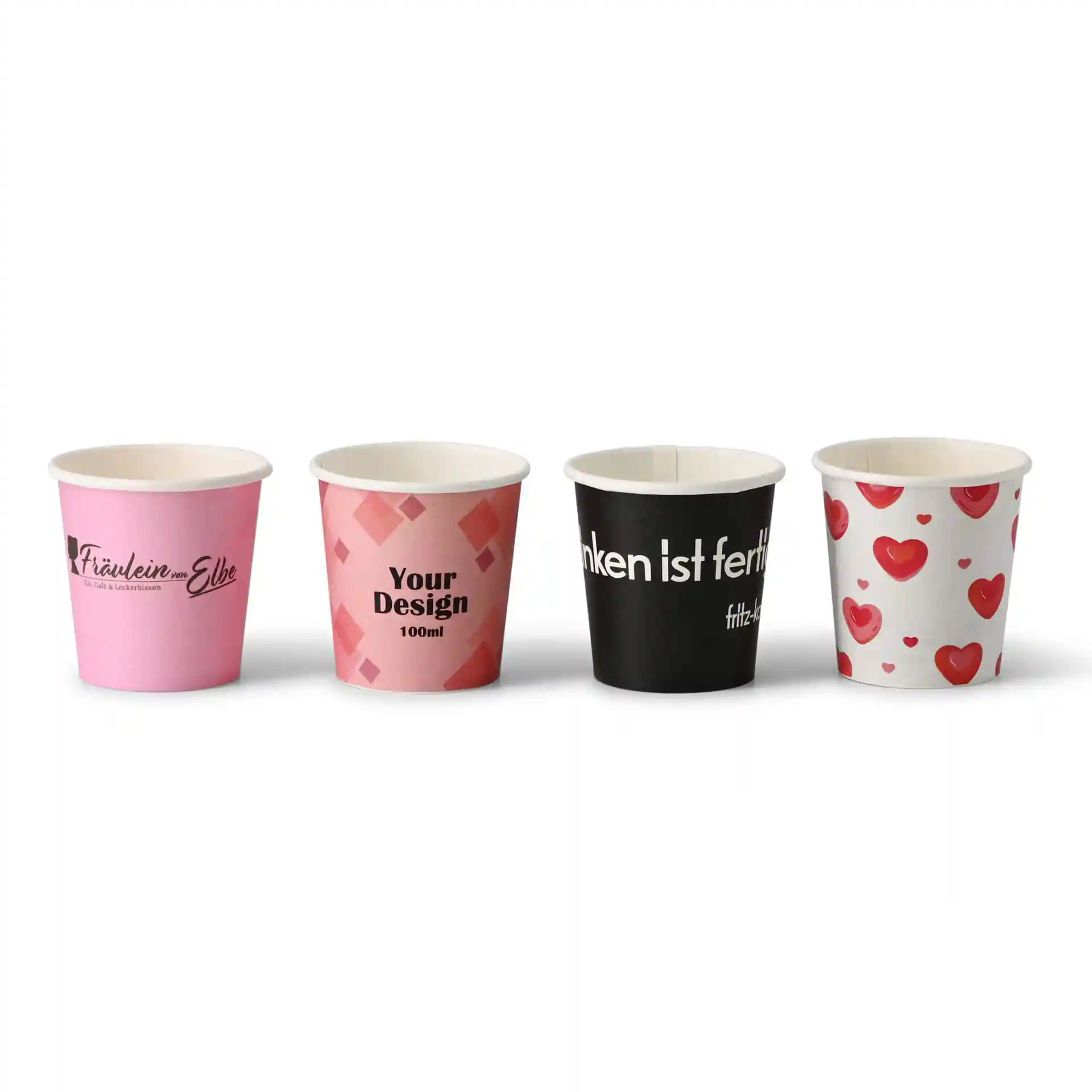 Four paper cups with various designs: pink with logo, pink geometric pattern, black with text, and white with hearts.