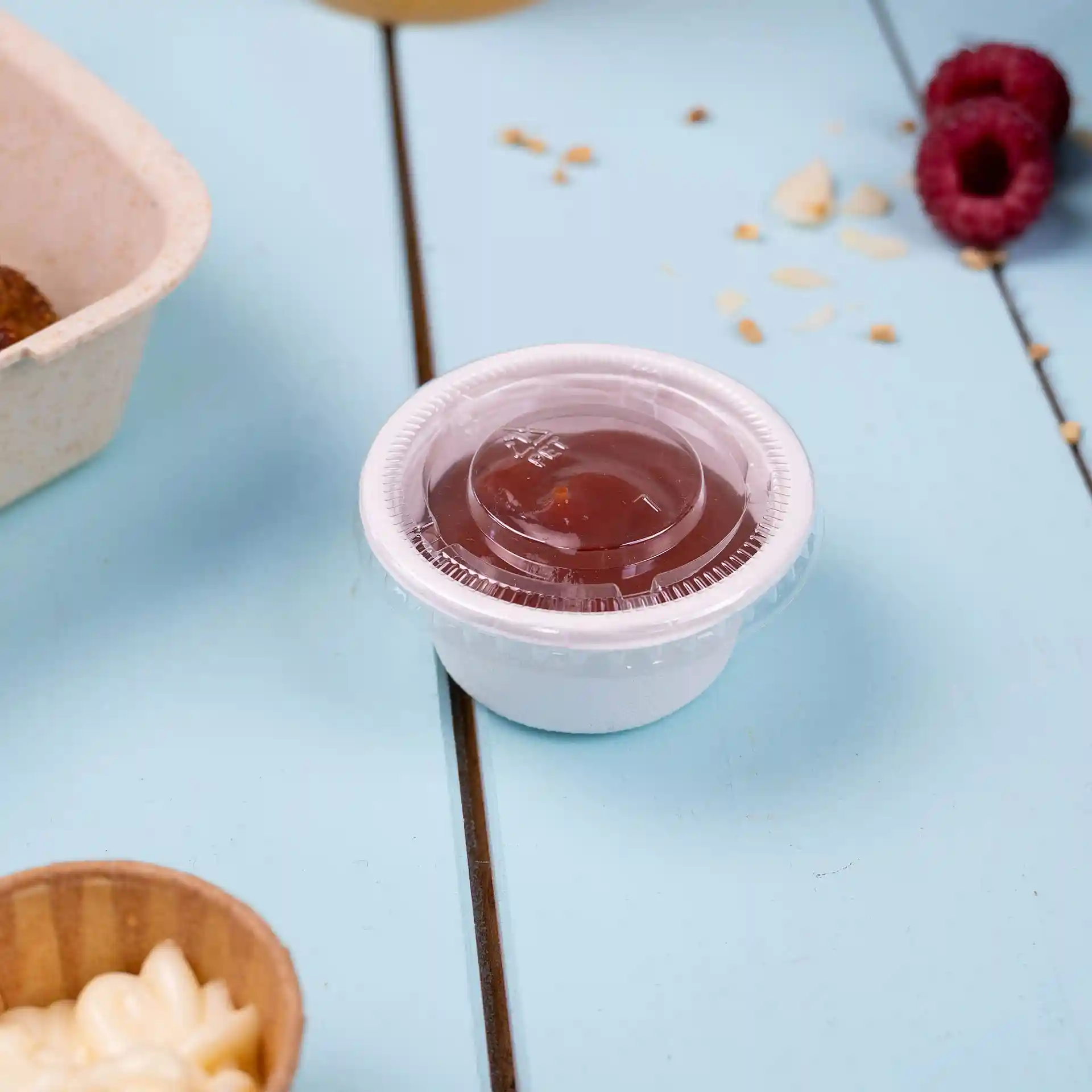 Clear round PET lid with a diameter of 64 mm, placed on a blue surface next to food items.