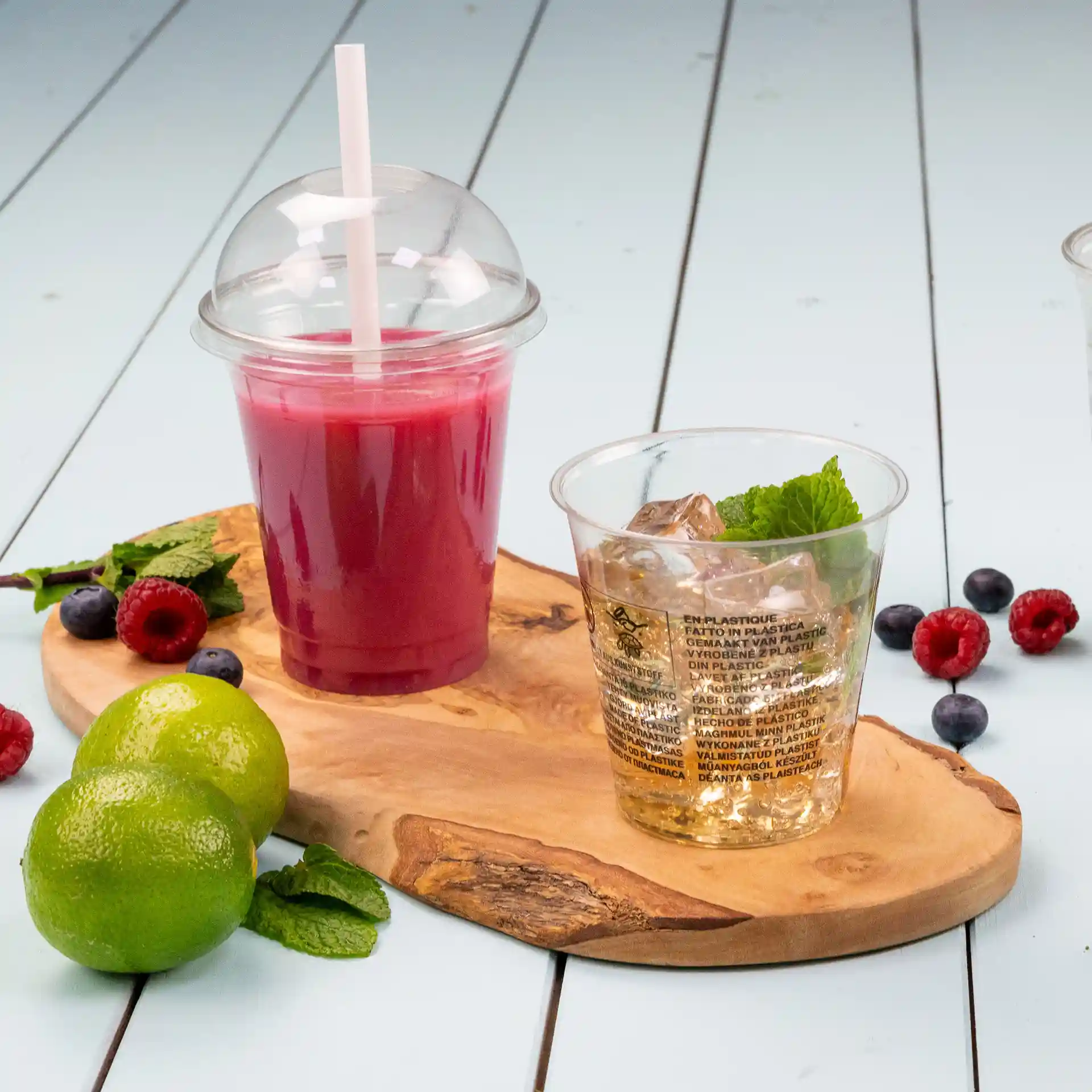 Image of a wooden serving board with a transparent 12 oz rPET cup filled with a pink drink and a second clear cup with ice and mint.