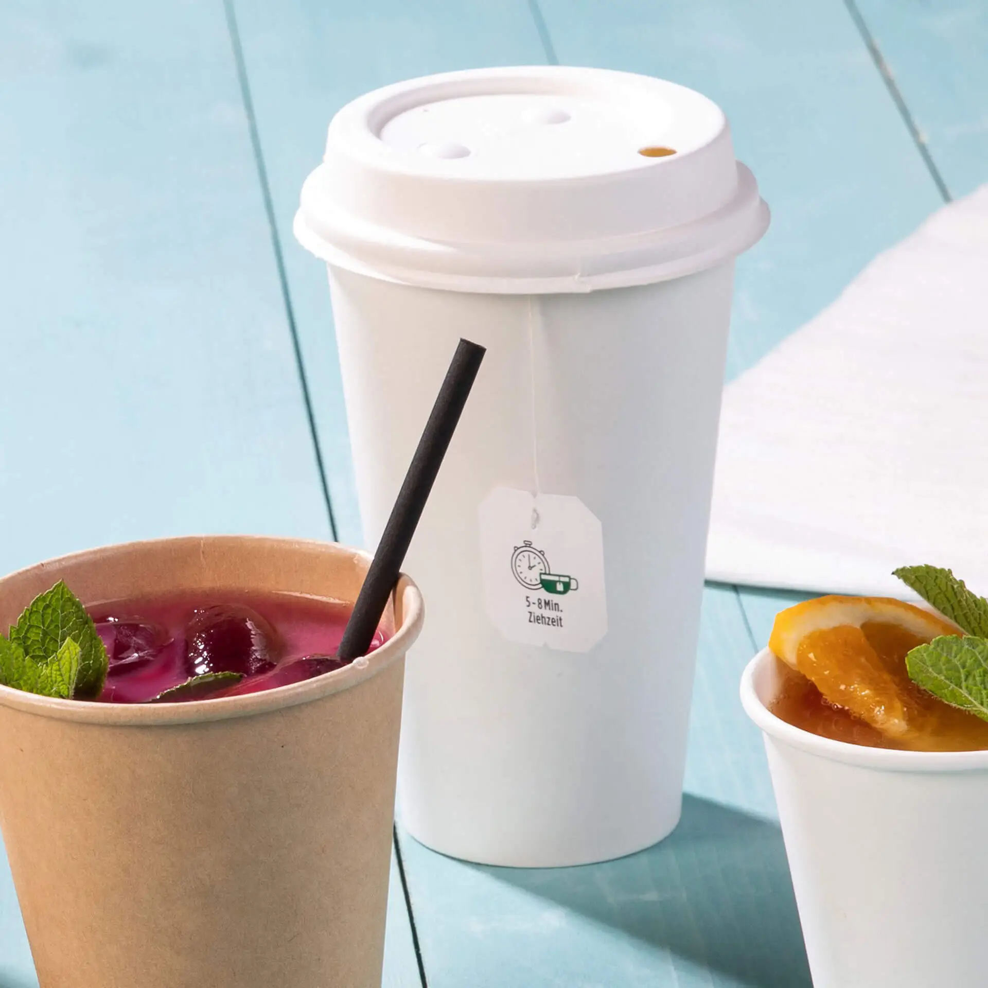 Single-wall white paper cup with PLA coating, suitable for hot and cold drinks, next to a paper cup with beverage and fruit.