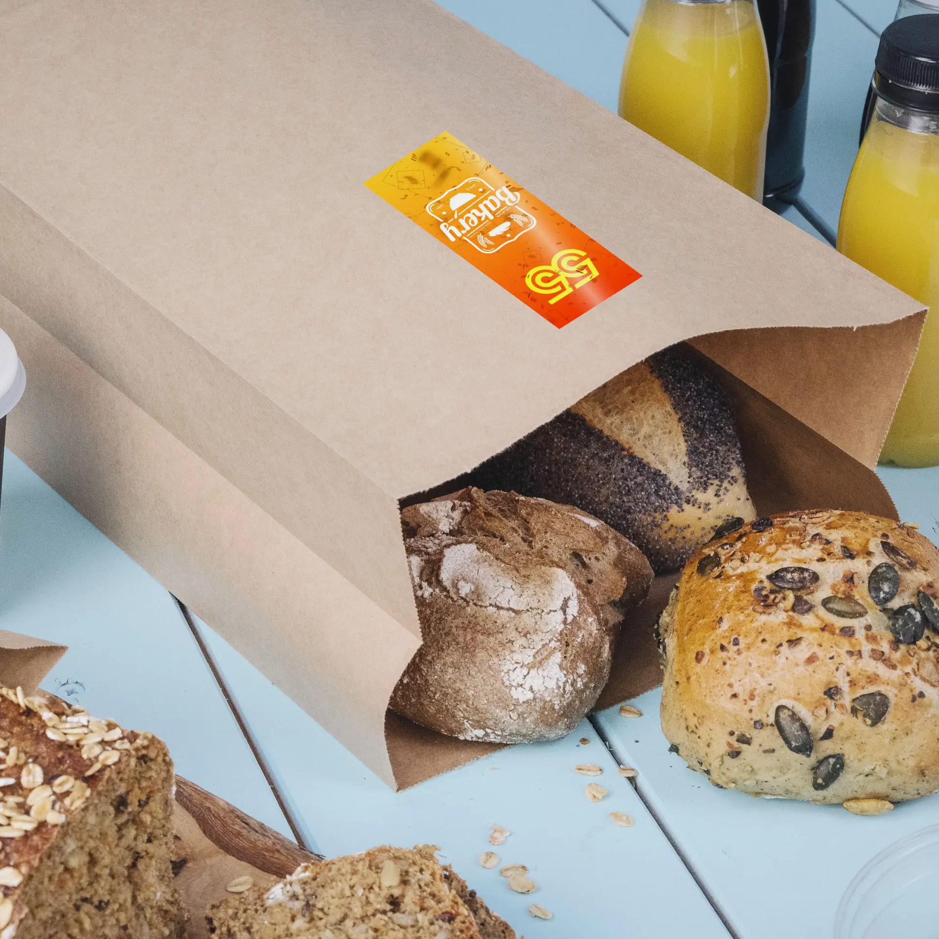 Brown paper bag containing several types of artisan bread peeking out, with a printed label visible on the bag.