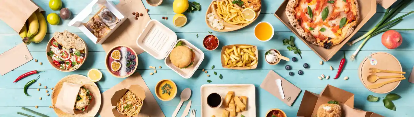 Eine Vielzahl von Lebensmitteln auf einer blauen Fläche, darunter Pizza, Salate, Burger und Desserts in Behältern.