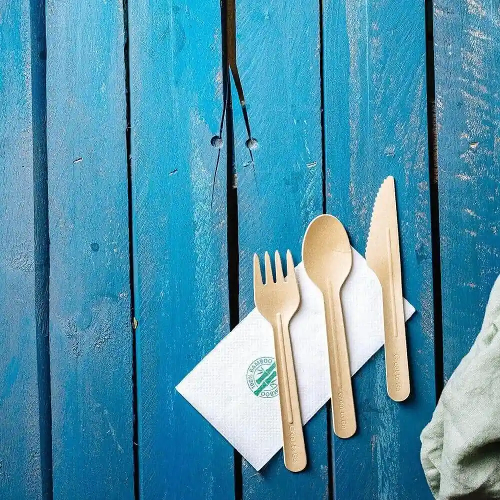 Brown paper knife, fork, and spoon arranged on a white napkin on a blue wooden surface.