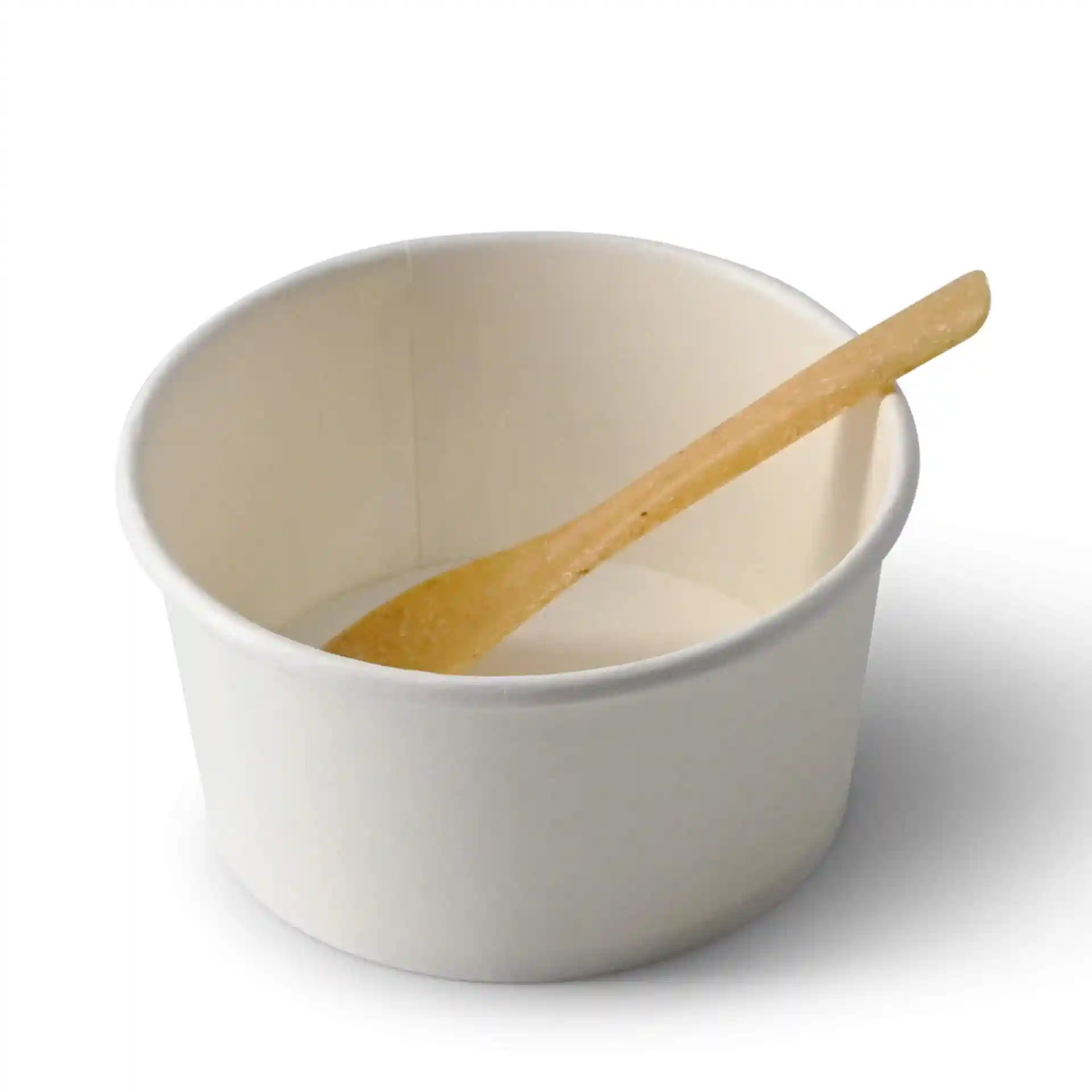 White paper cup with a caramel-colored wooden spoon resting inside.
