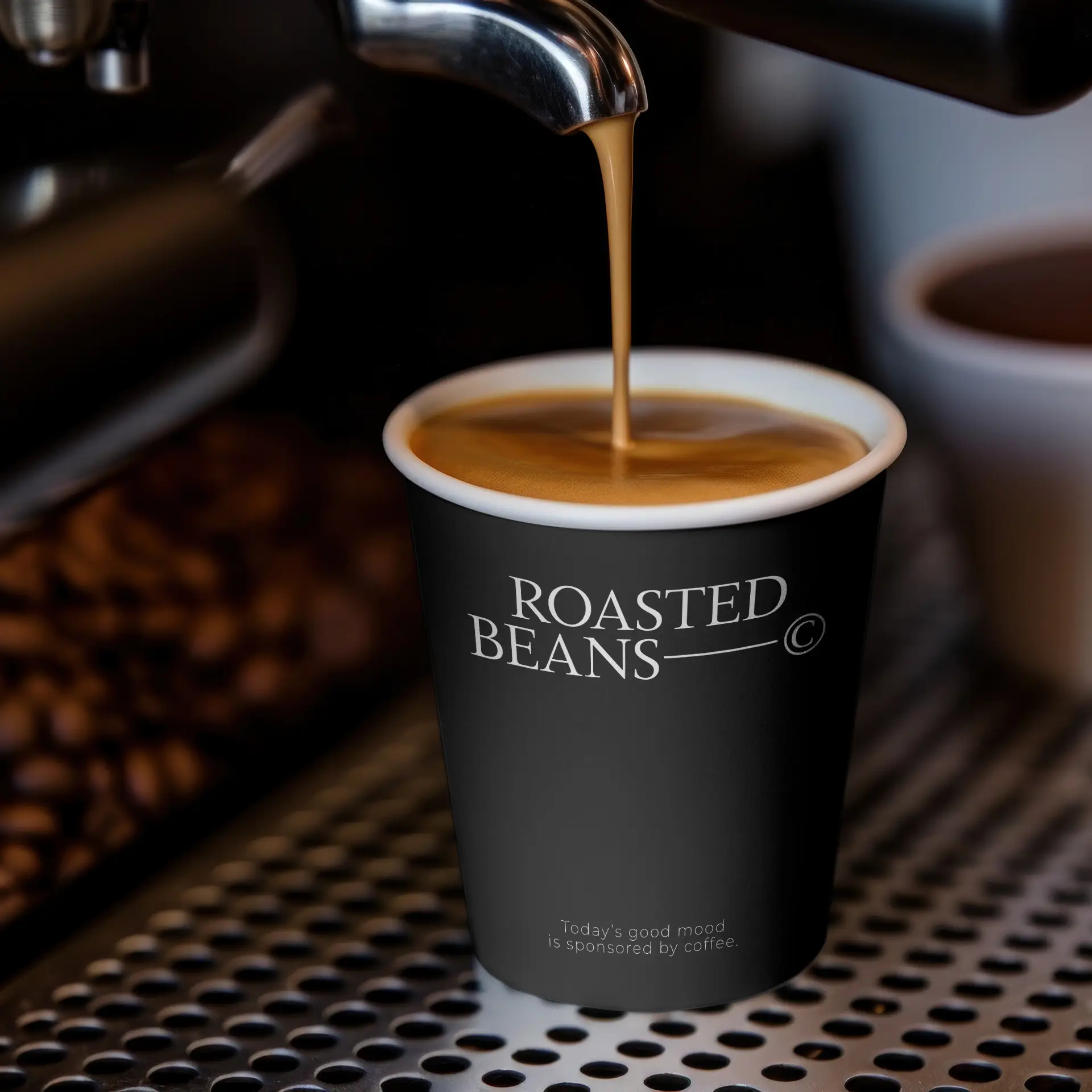Schwarzer Becher mit "ROASTED BEANS"-Logo, gefüllt mit Kaffee, auf einem Ablageteller der Kaffeemaschine.
