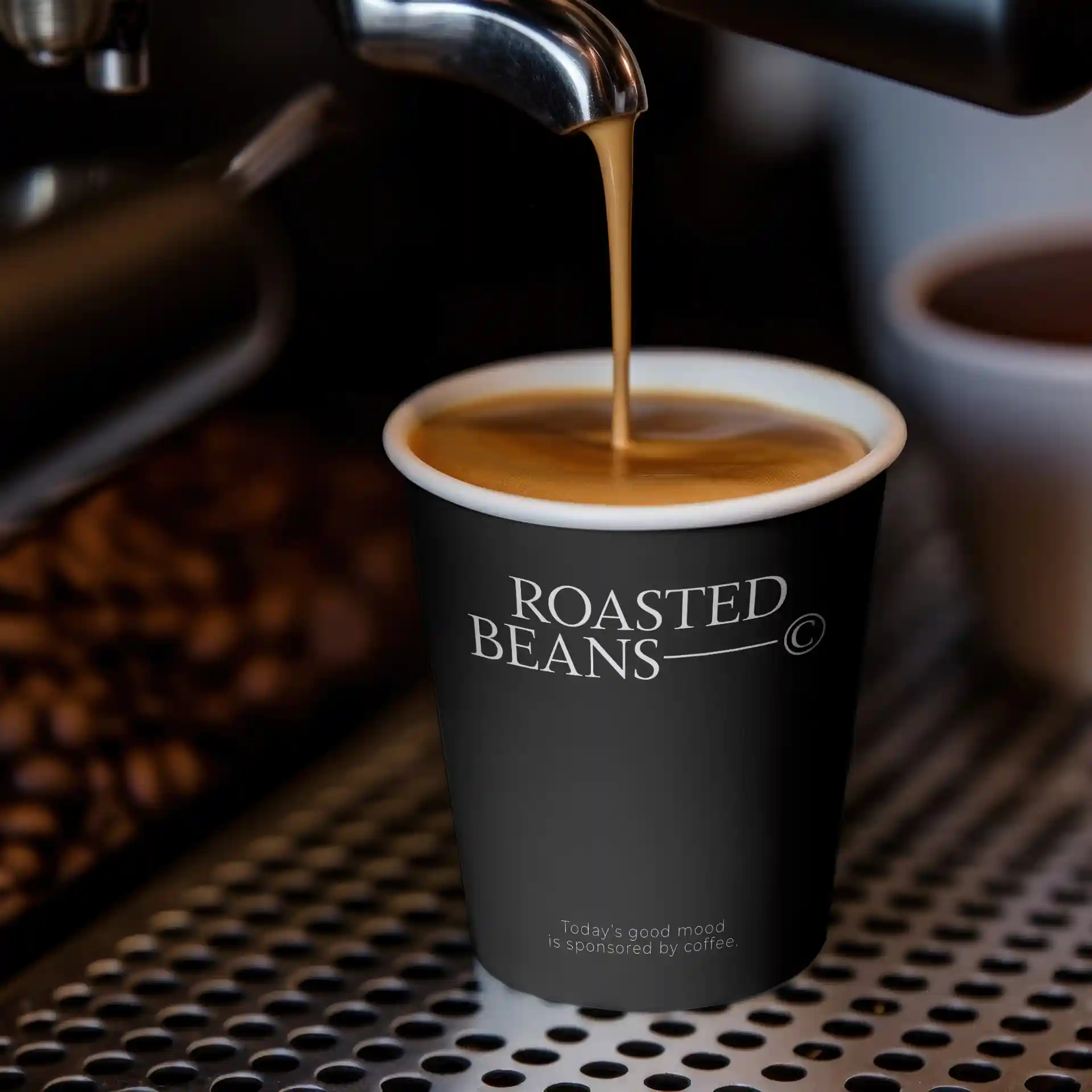 Black paper cup with logo, filled with coffee, placed on a metallic surface with coffee beans in the background.