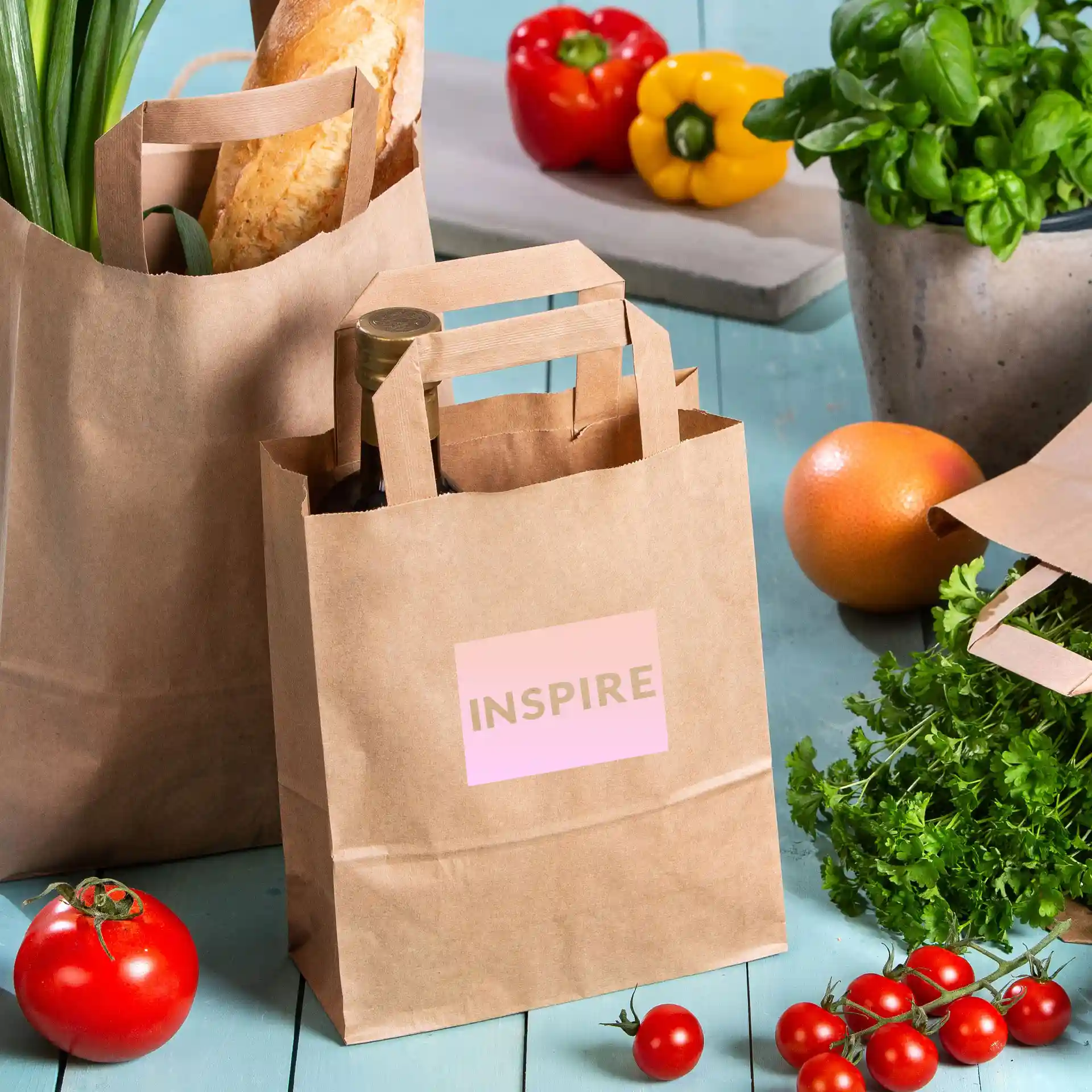 Brown kraft paper bag with a pink label displaying the word "INSPIRE," surrounded by vegetables and fruits.