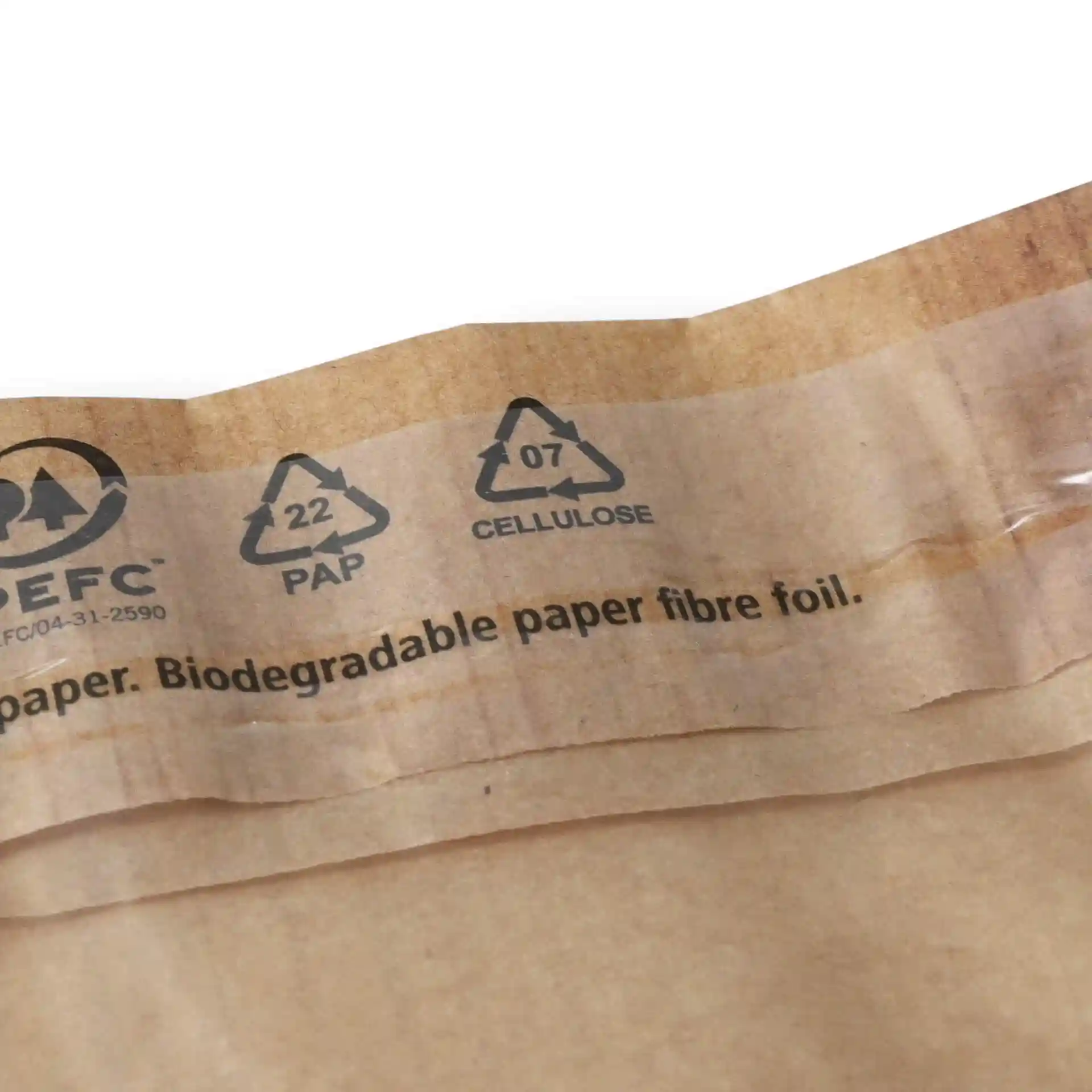 Brown snack bag with a window and adhesive seal, showing recycling symbols and printed text on the top edge.