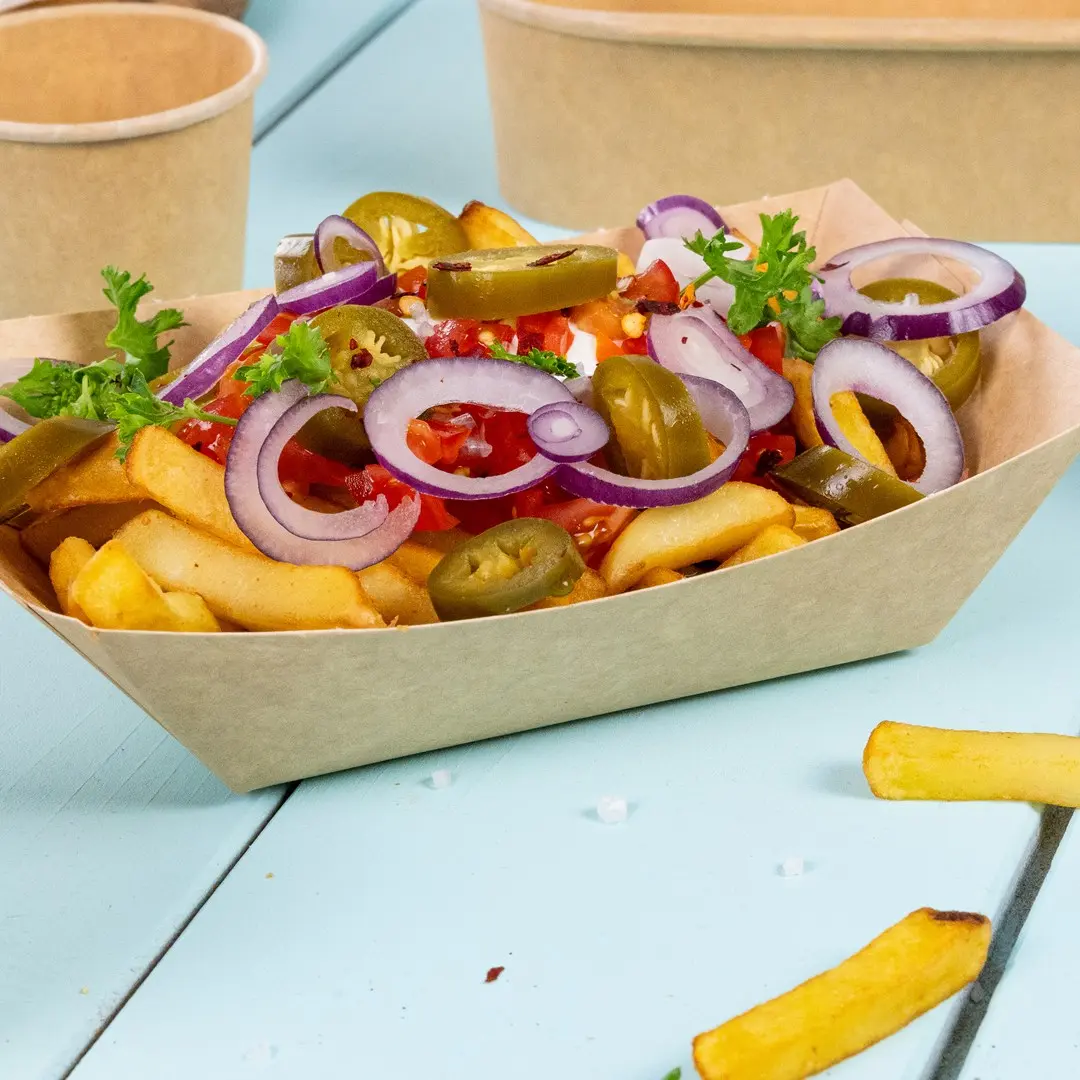 Bowl of fries topped with sliced onions, jalapeños, diced tomatoes, and parsley on a blue surface.
