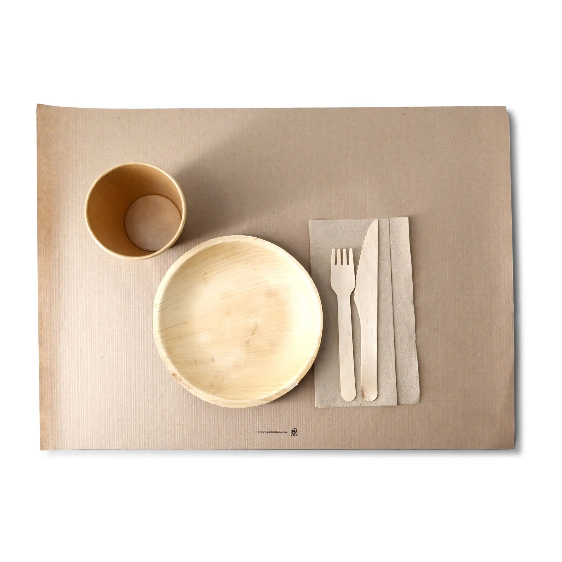 Image of a rPaper placemat with a bowl, cup, wooden fork, knife, and napkin arranged on it.