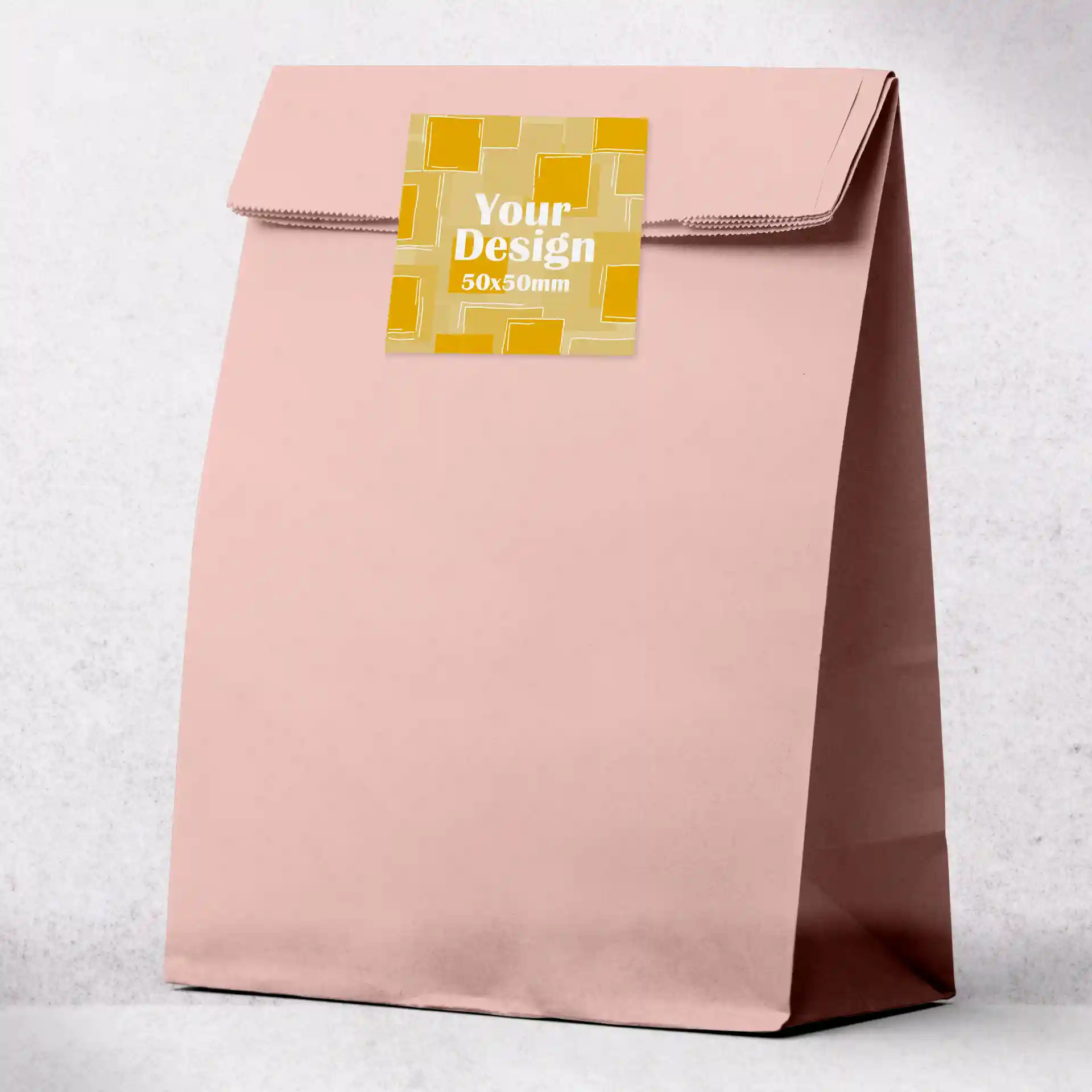 Pink paper bag with a square printed label on the front, measuring 50 x 50 mm.