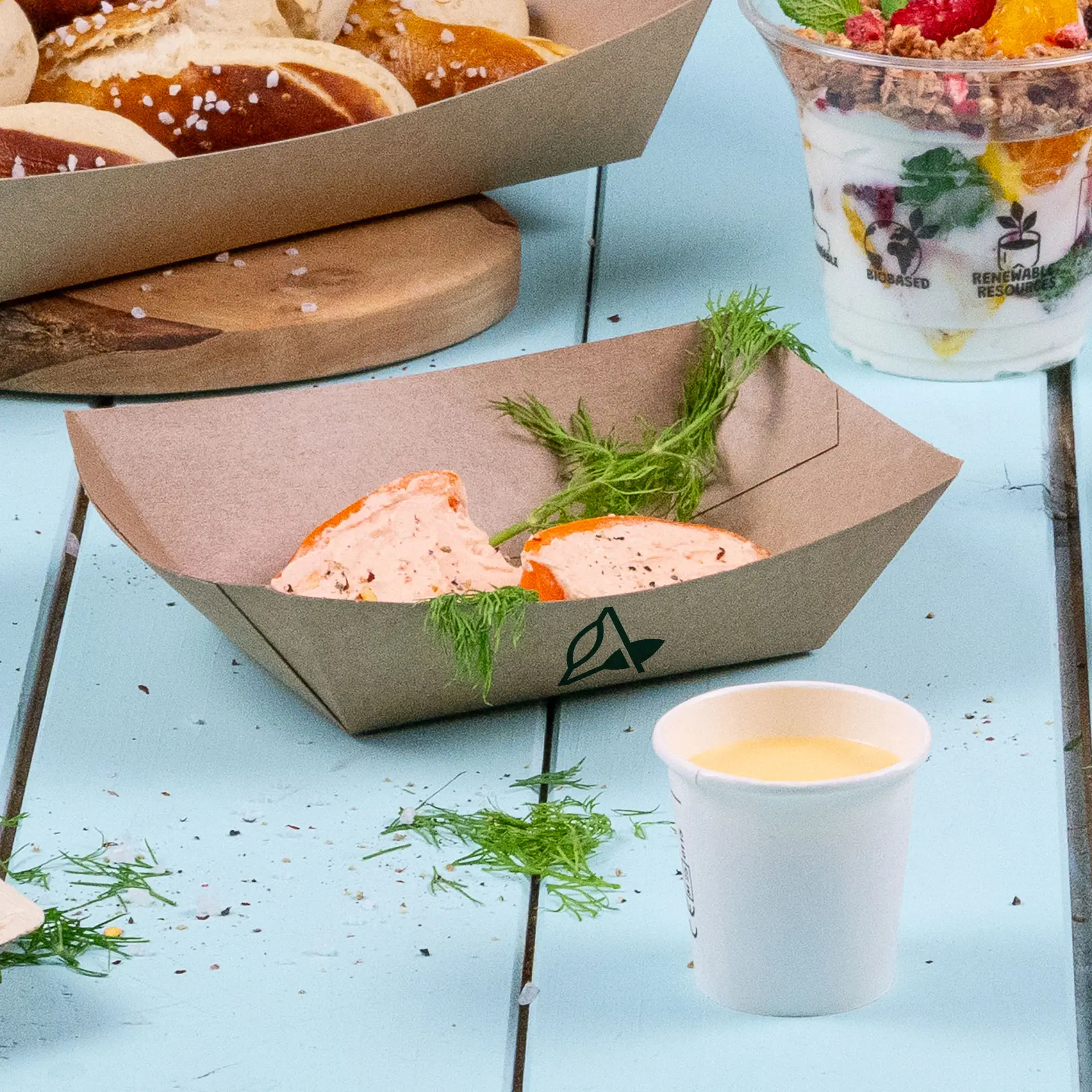 Brown custom-printed snack tray, 200 ml, containing two portions of creamy dip and garnished with herbs, with a small cup nearby.