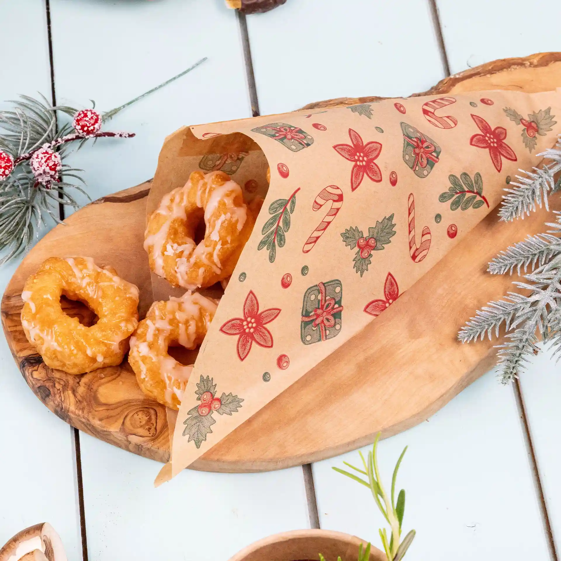 Braune fettdichte Tüte mit Winterdesign, enthält drei glasierte Donuts auf einem Holztablett.