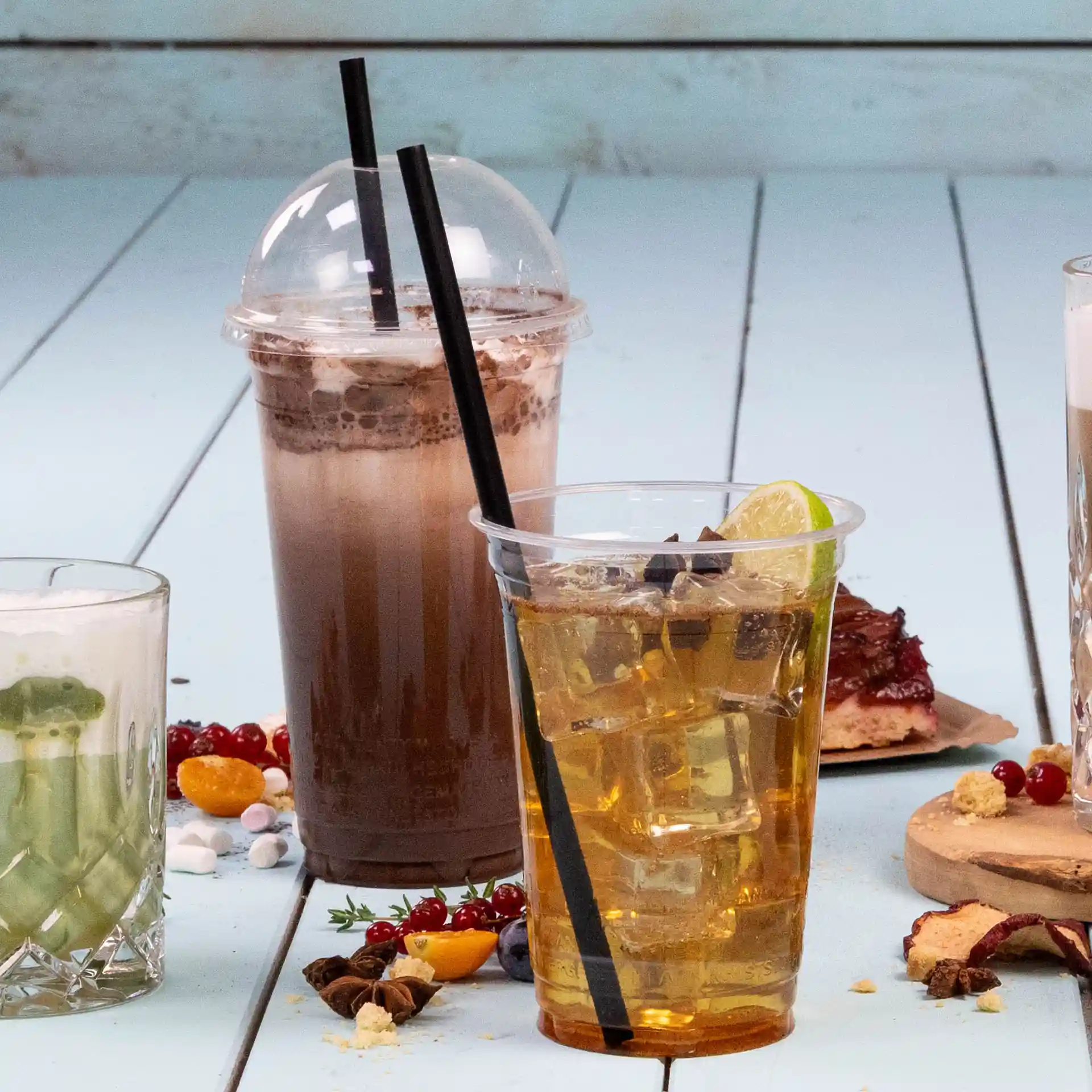 Bild von drei Getränken: ein Schokoladengetränk in einem klaren Becher, ein Eistee mit einer Zitronenscheibe und ein grünes Getränk in einem Glas.