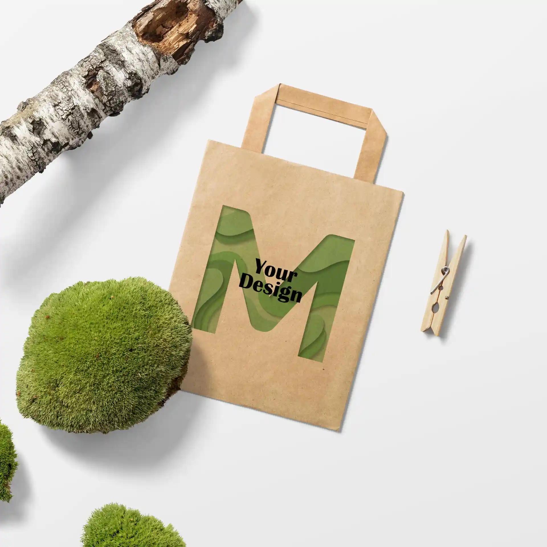 Brown paper carrier bag with a rectangular shape, featuring a cut-out design of the letter 'M' and the phrase 'Your Design'.