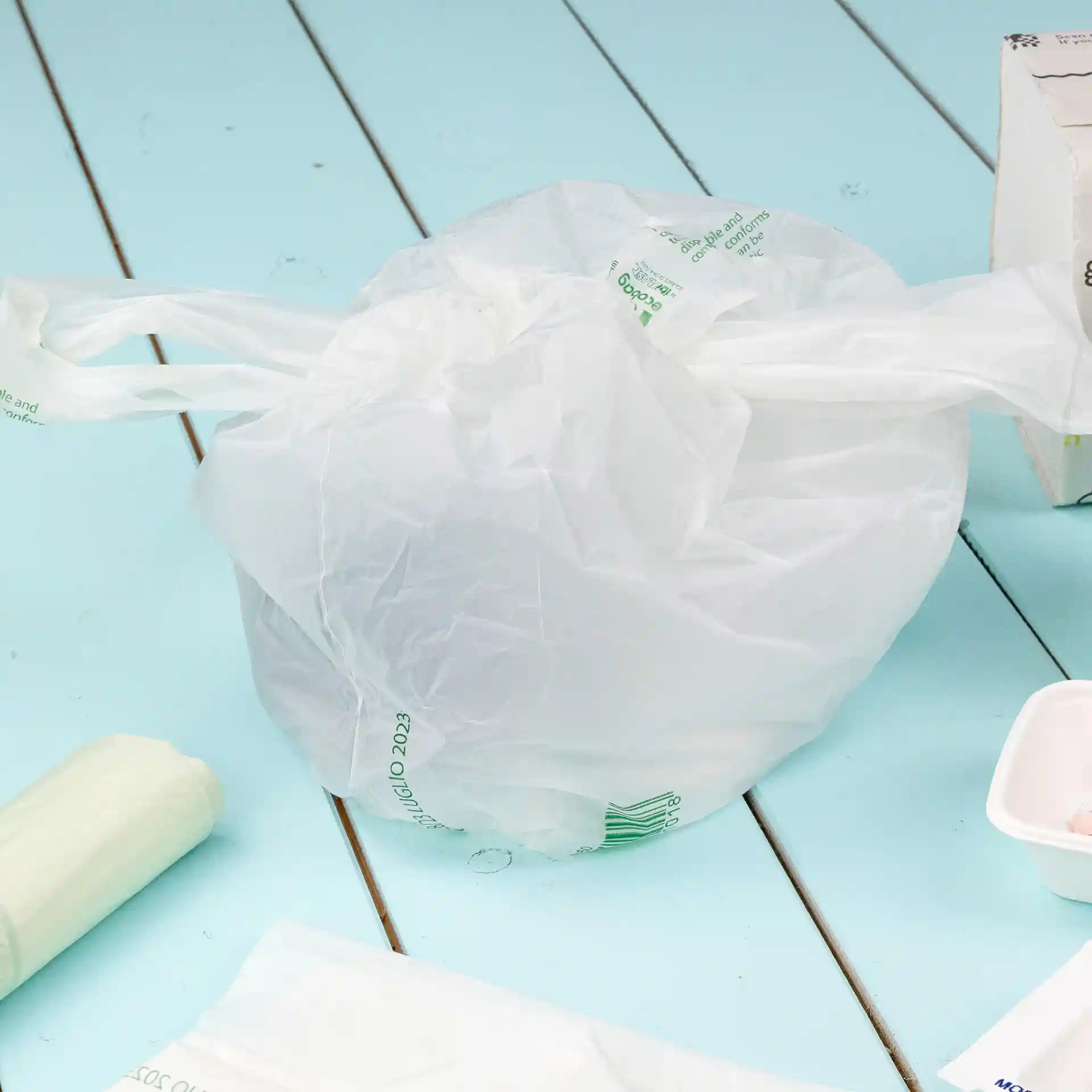 Transparent bag made of PLA material, tied at the top, placed on a blue surface.