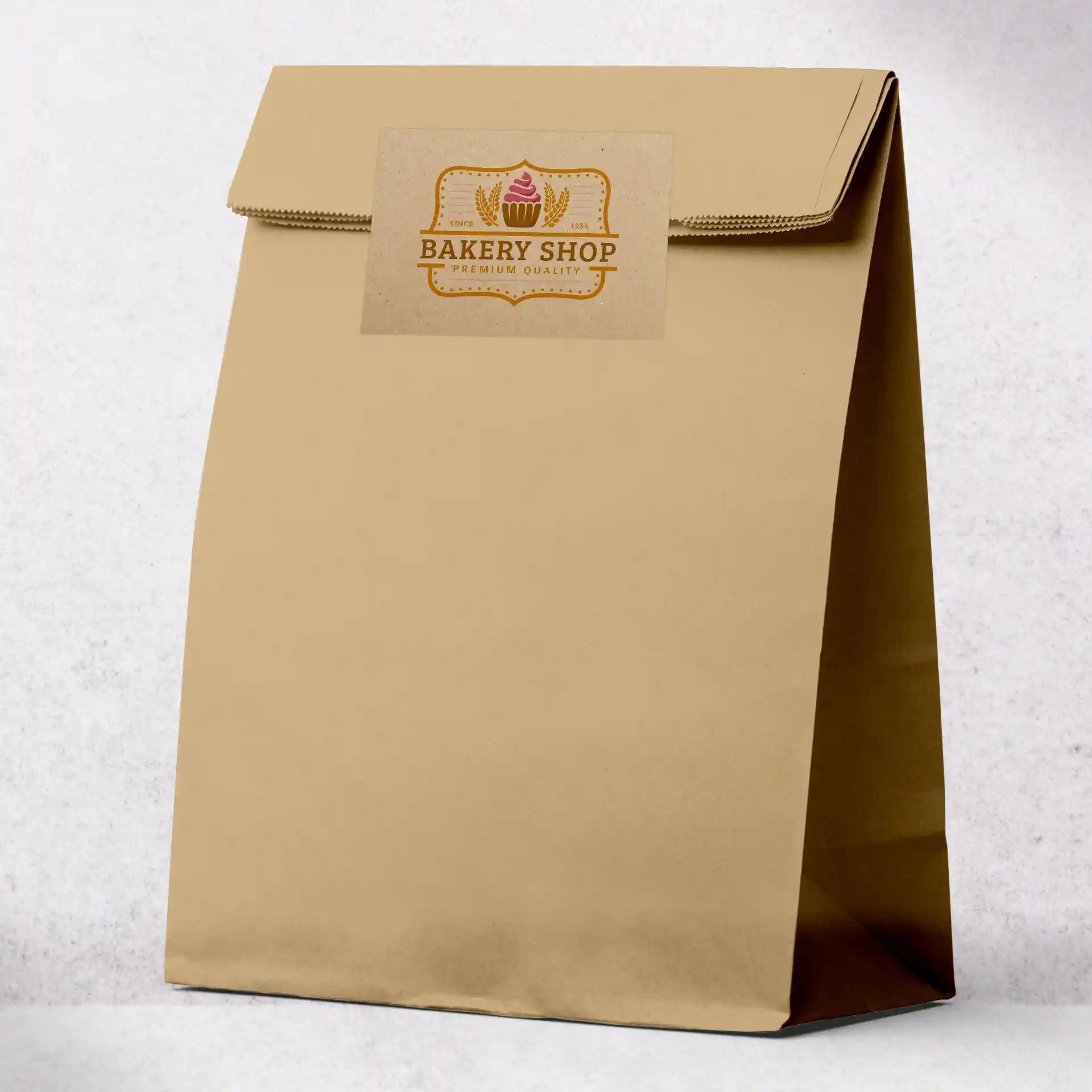 Brown kraft paper bag with a rectangular printed label featuring a cupcake design.