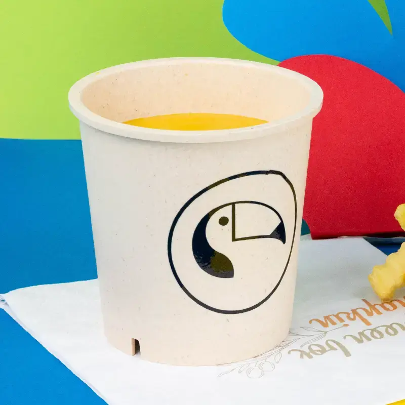 Dark green reusable cup filled with a vegetable dish, featuring a customizable design area marked "Your Design."