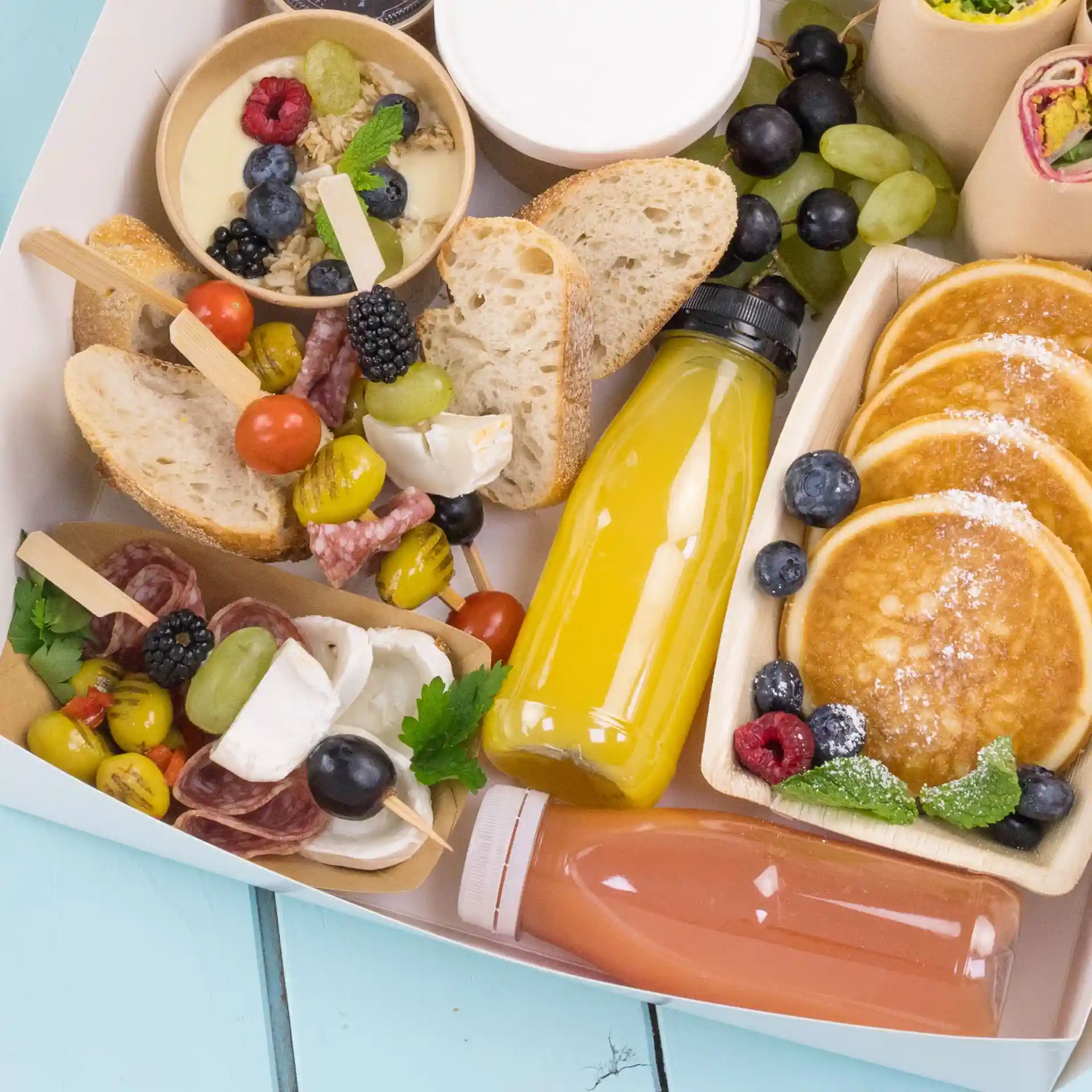 Bild eines Essensplatten mit Pfannkuchen, Brot, Obst und Getränken in klaren rPET-Flaschen.