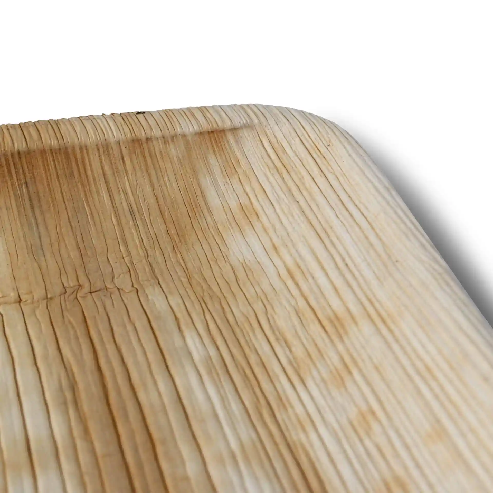 Close-up of a square palm leaf plate with a textured grain surface and rounded corners.