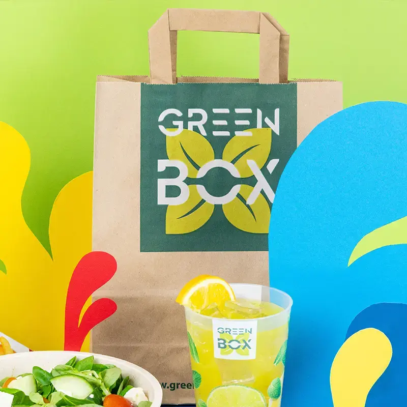 Brown paper bag with customizable design featuring the text "Your Design" and a large letter "S," surrounded by fresh produce.