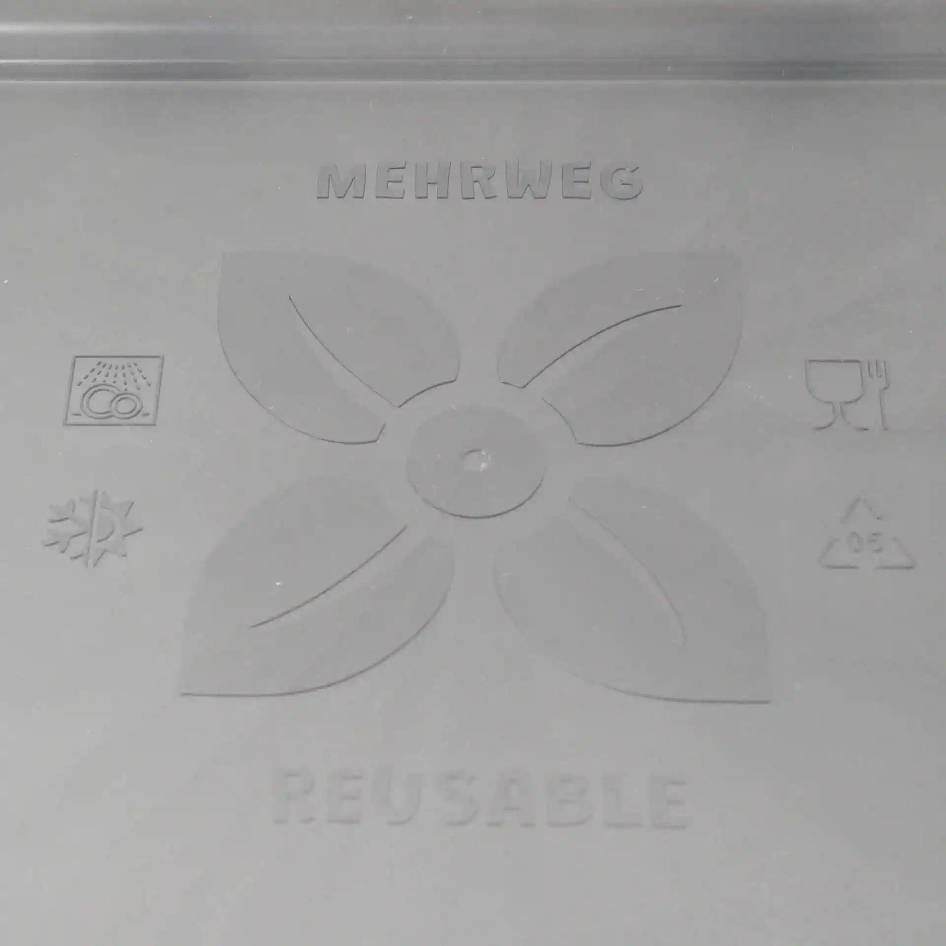 Schematische Zeichnung eines grauen wiederverwendbaren Deckels mit Blattdesign und verschiedenen Symbolen auf einem einfarbigen Hintergrund.