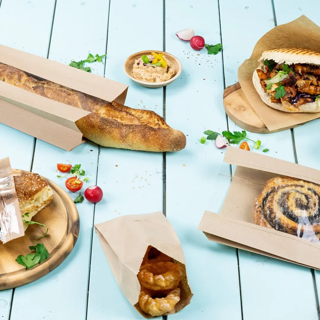 Image of various baked goods including a baguette, sandwich, pastries, and a bowl of dip on a blue wooden surface.