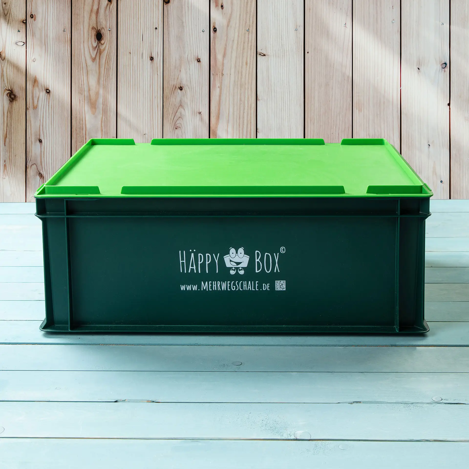 Eine grüne wiederverwendbare Aufbewahrungsbox mit Deckel, mit dem Aufkleber "HAPPY Box" an der Seite.