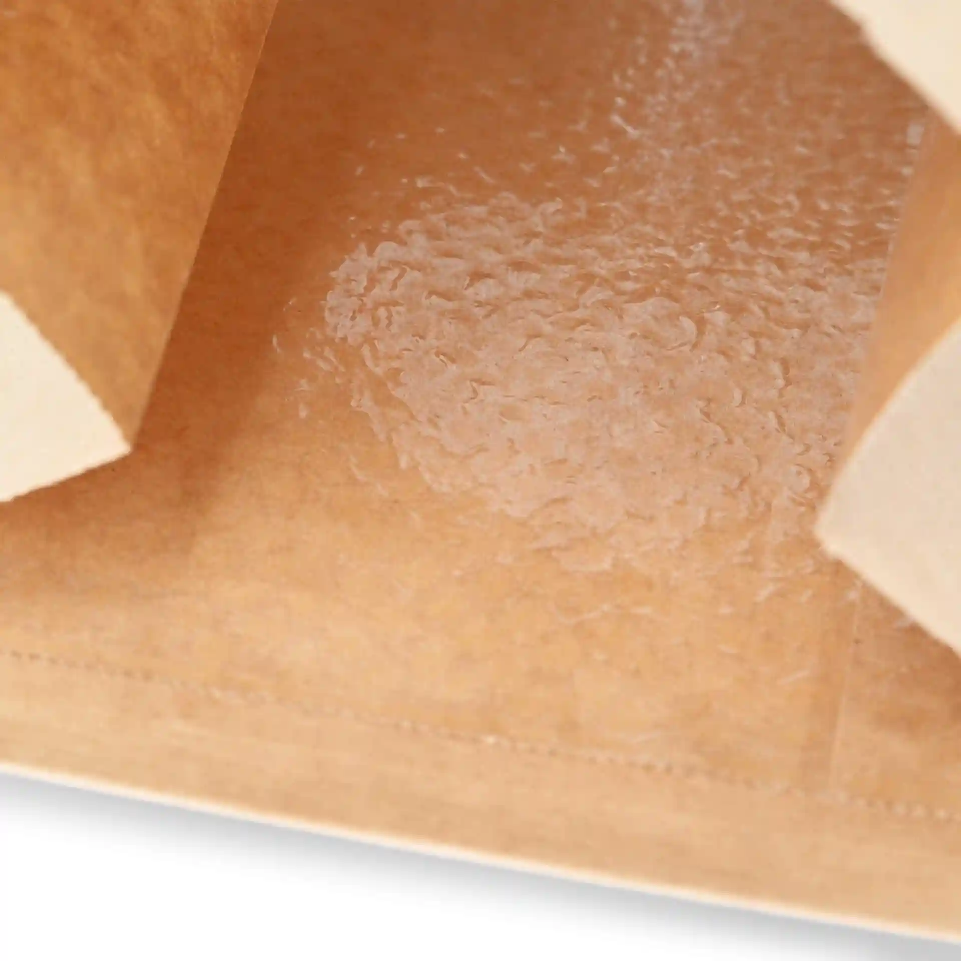 Nahaufnahme des Innenraums einer braunen Kraftpapiertüte mit klarem Sichtfenster und glatter, beschichteter Oberfläche.