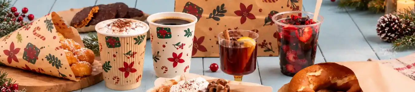 A variety of festive food and drinks, including cups, a dessert cone, and a fruit drink, arranged on a blue wooden surface.