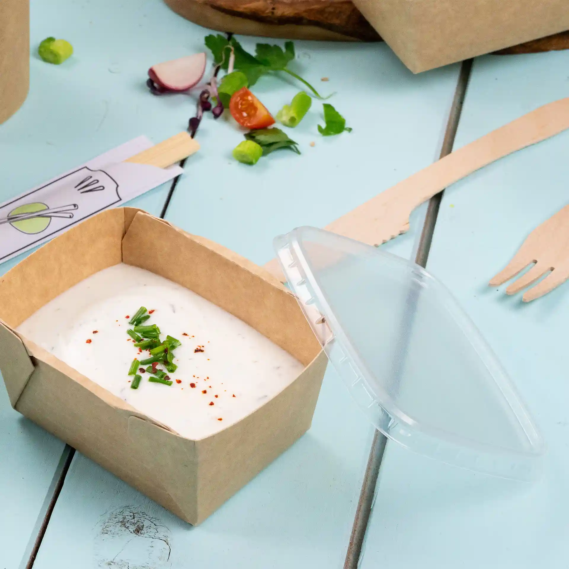 Rectangular cardboard container with a clear rPET lid, filled with a creamy dip and garnished with chives and spices.
