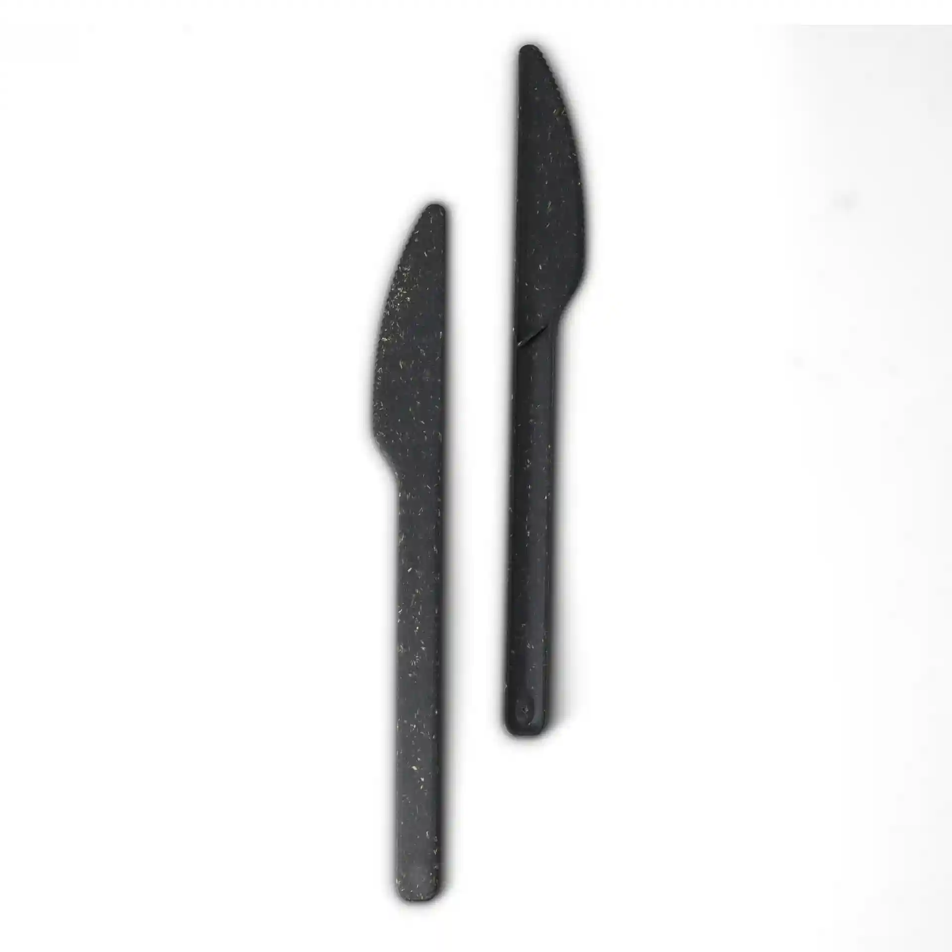 Two black reusable knives made from bio compound, each with a curved blade and a handle.