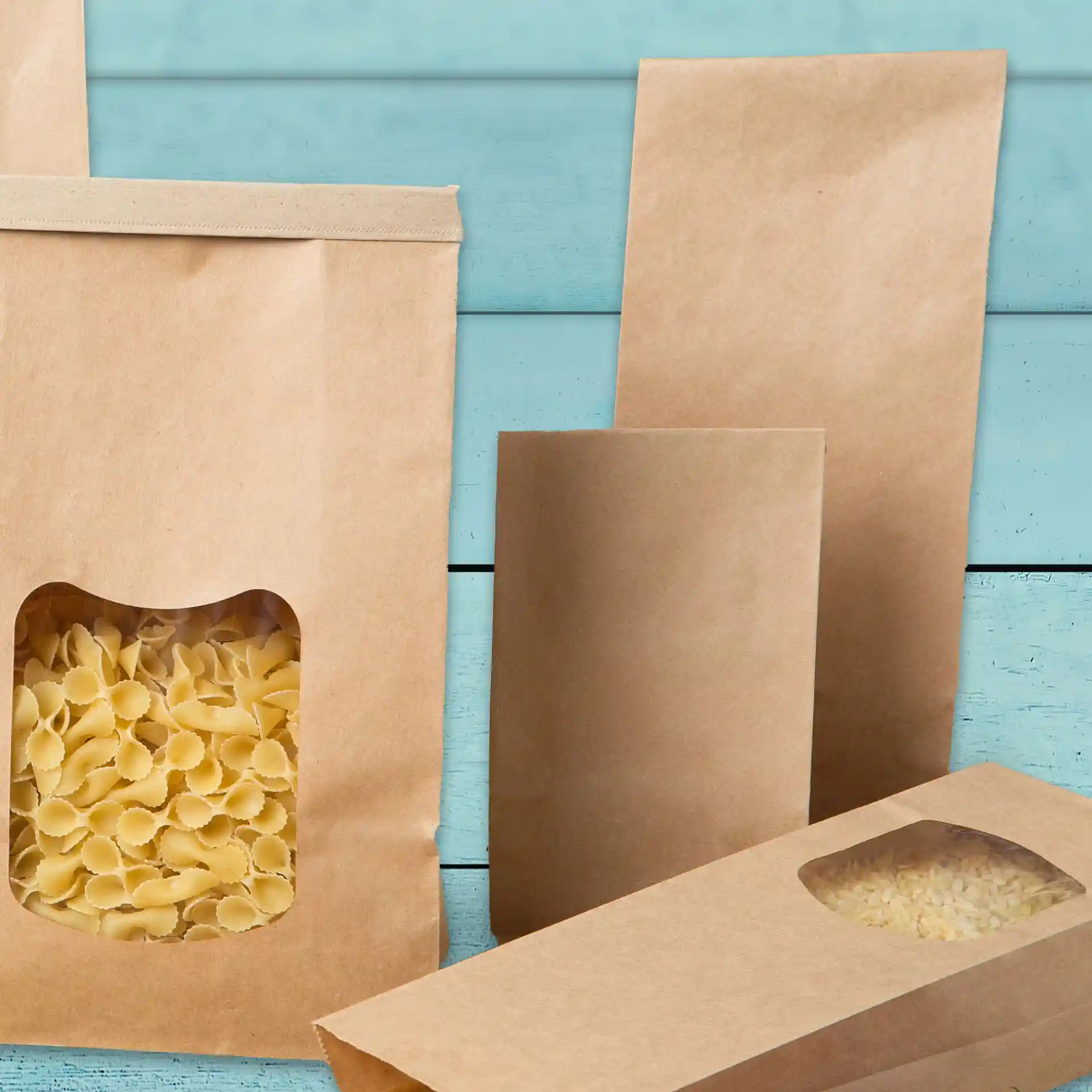 Braune Kraftpapiertüten in verschiedenen Größen, eine Tüte zeigt Pasta durch ein transparentes Fenster.