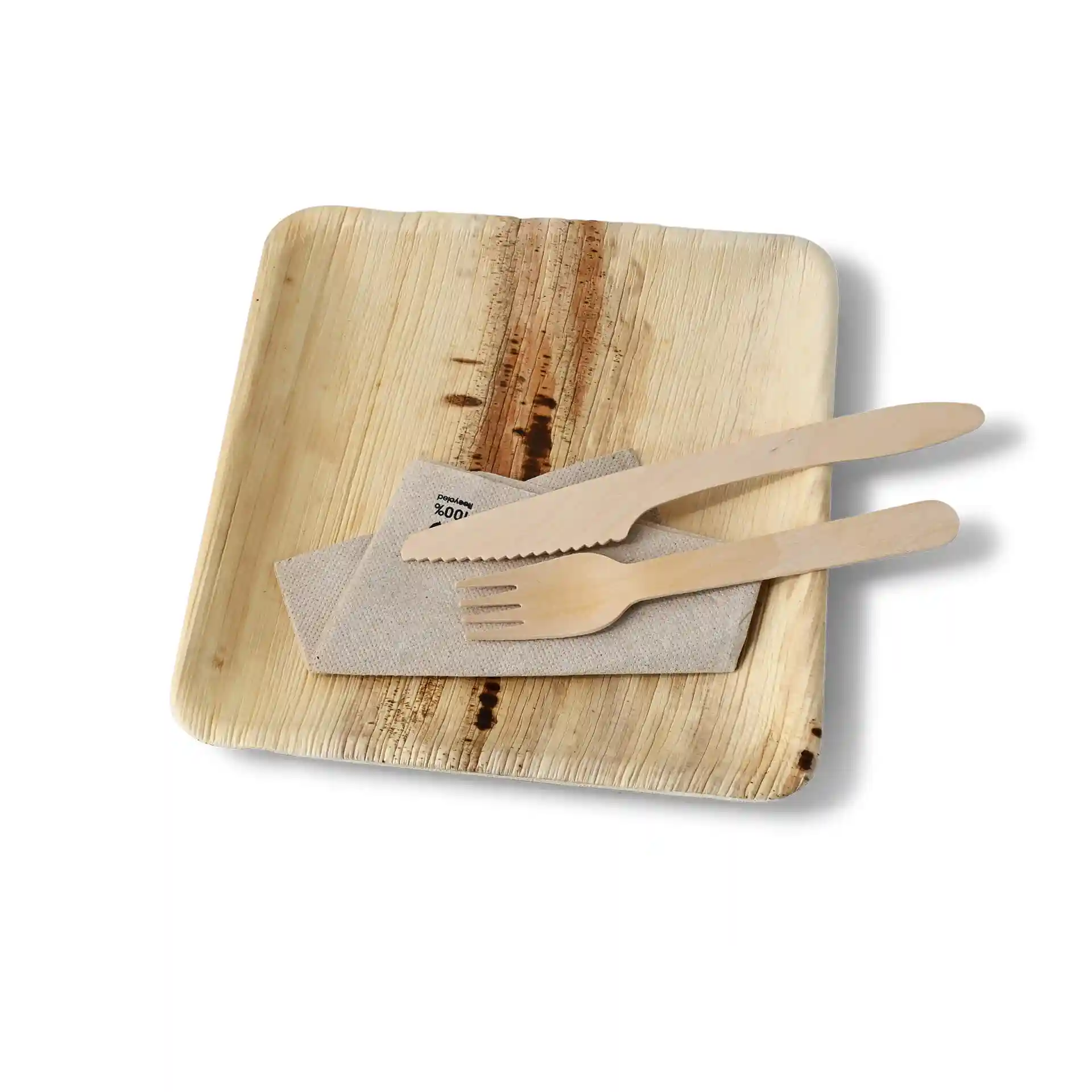 Square palm leaf plate with a grain finish, accompanied by a cloth napkin and wooden knife and fork.