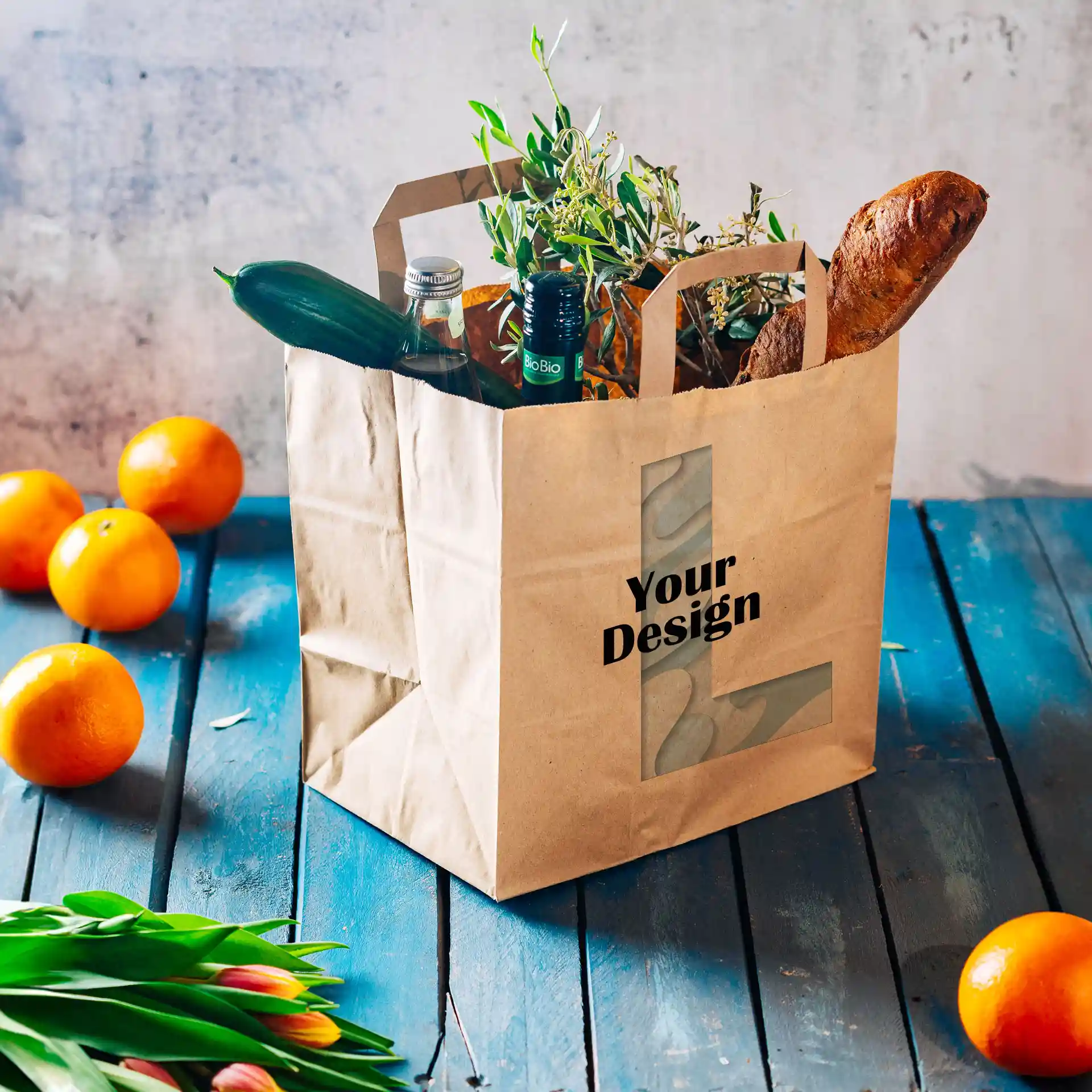 Brown paper carrier bag with a wide base, filled with vegetables, bottles, and a baguette, on a blue wooden surface.