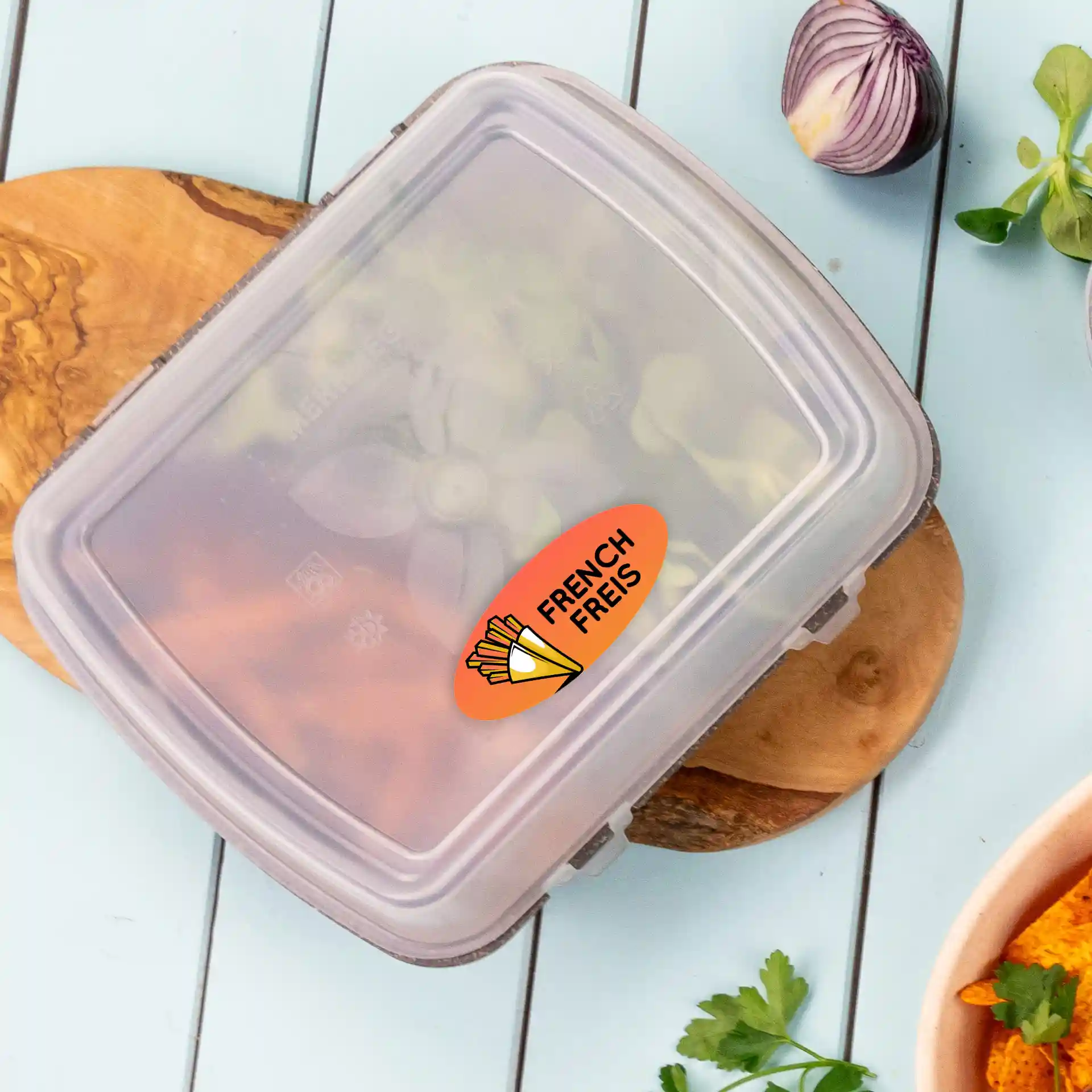 Container with a clear lid holding vegetables, featuring an oval label with a design of French fries.
