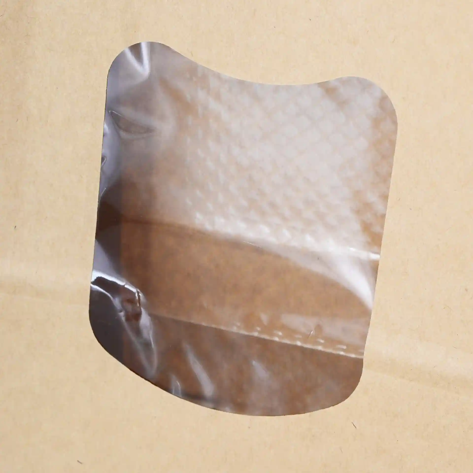 Transparent viewing window on a brown kraft paper bag with a rounded edge.