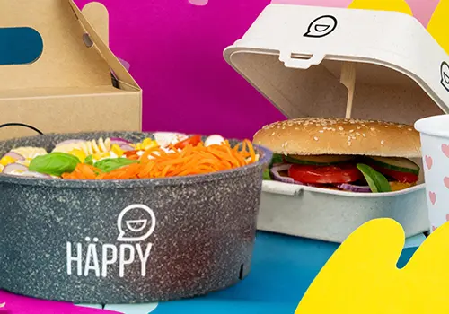 Stack of colorful food bowls labeled "HAPPY BOWL" in various designs, with a separate food container in the background.