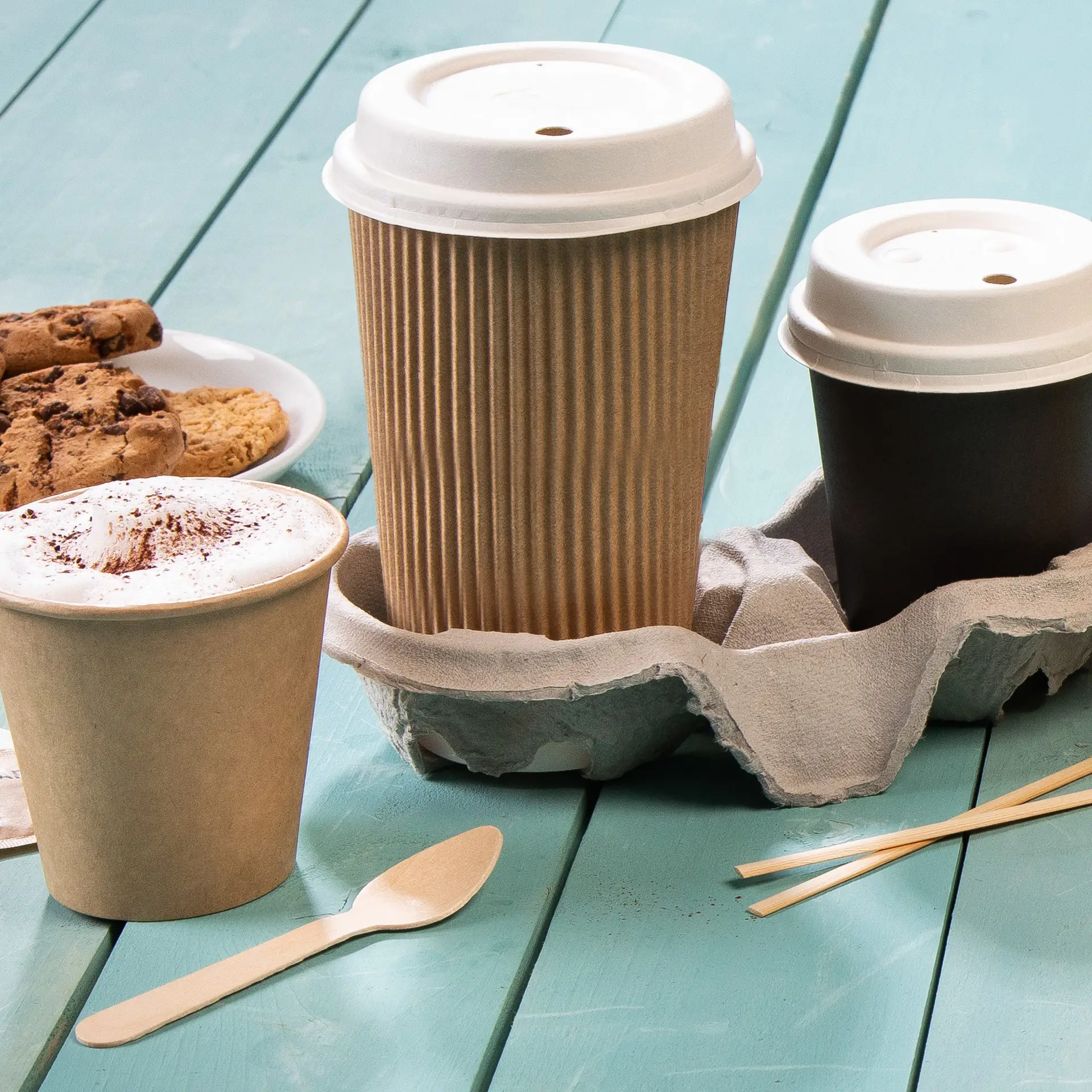 Drei Becher in einem Halter auf einer blauen Fläche; beinhaltet einen 16 oz gerippten braunen Becher und einen Becher mit weißem Inneren.