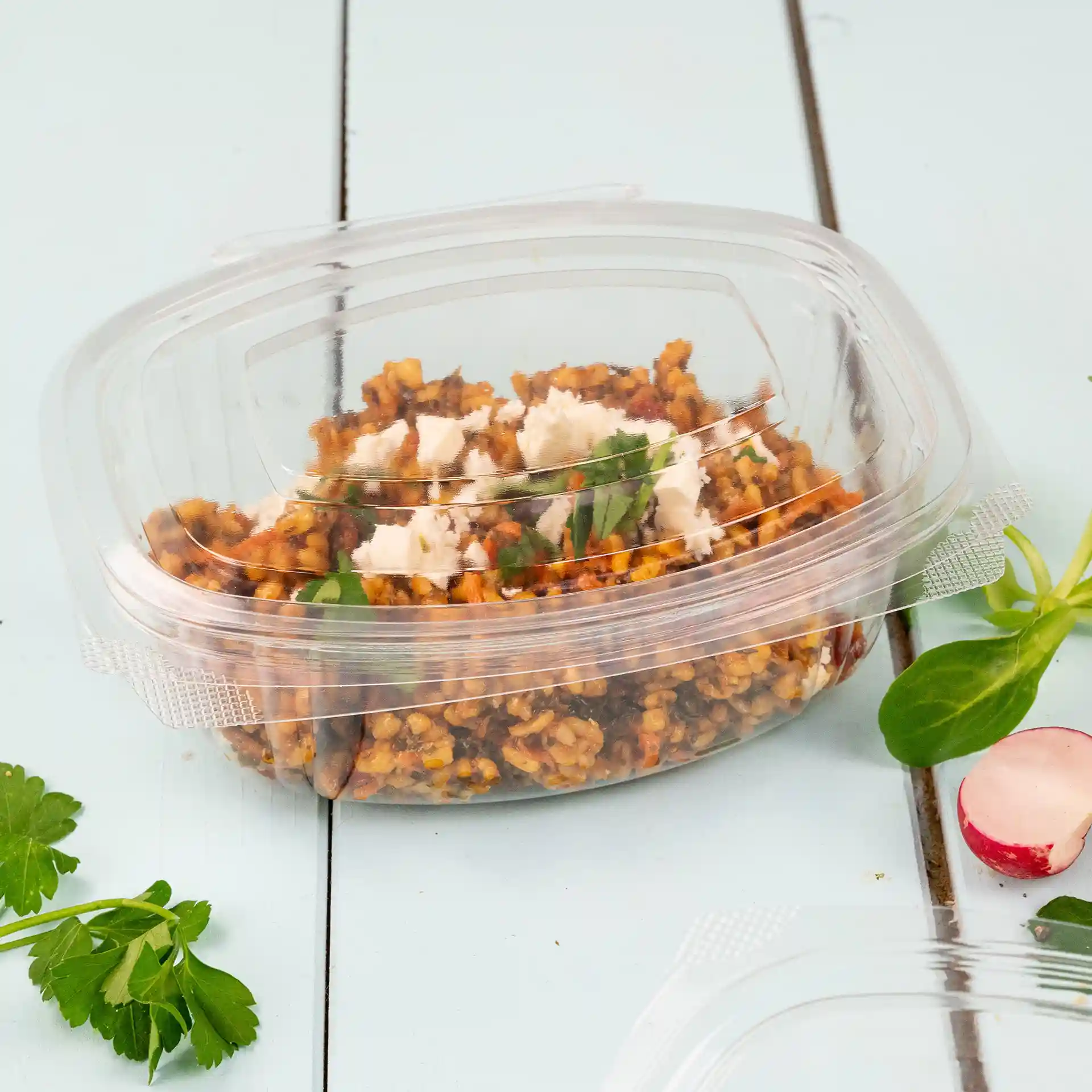 Transparent rectangular PLA deli bowl with a folding lid, containing a mixed food item and garnished with herbs.