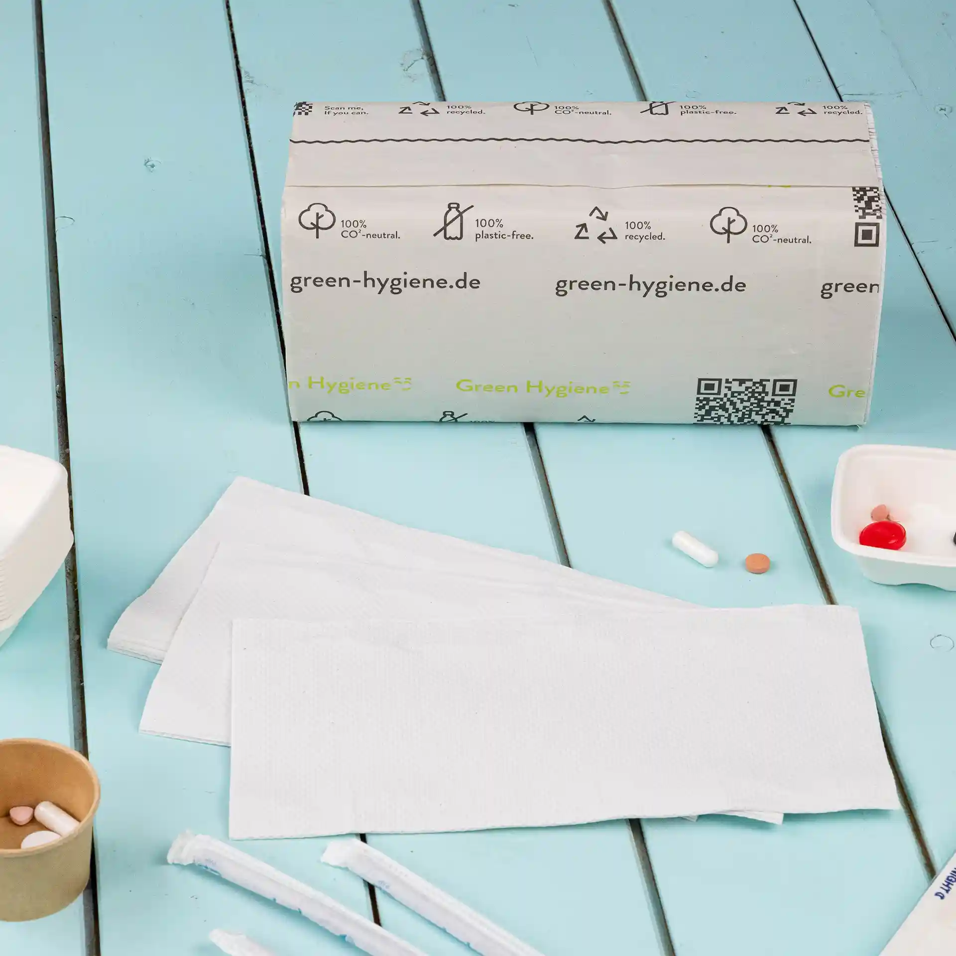 Packung mit gefalteten rPaper-Handtüchern, 2-lagig, V-Faltung, mehrere Handtücher auf einer blauen Oberfläche sichtbar.